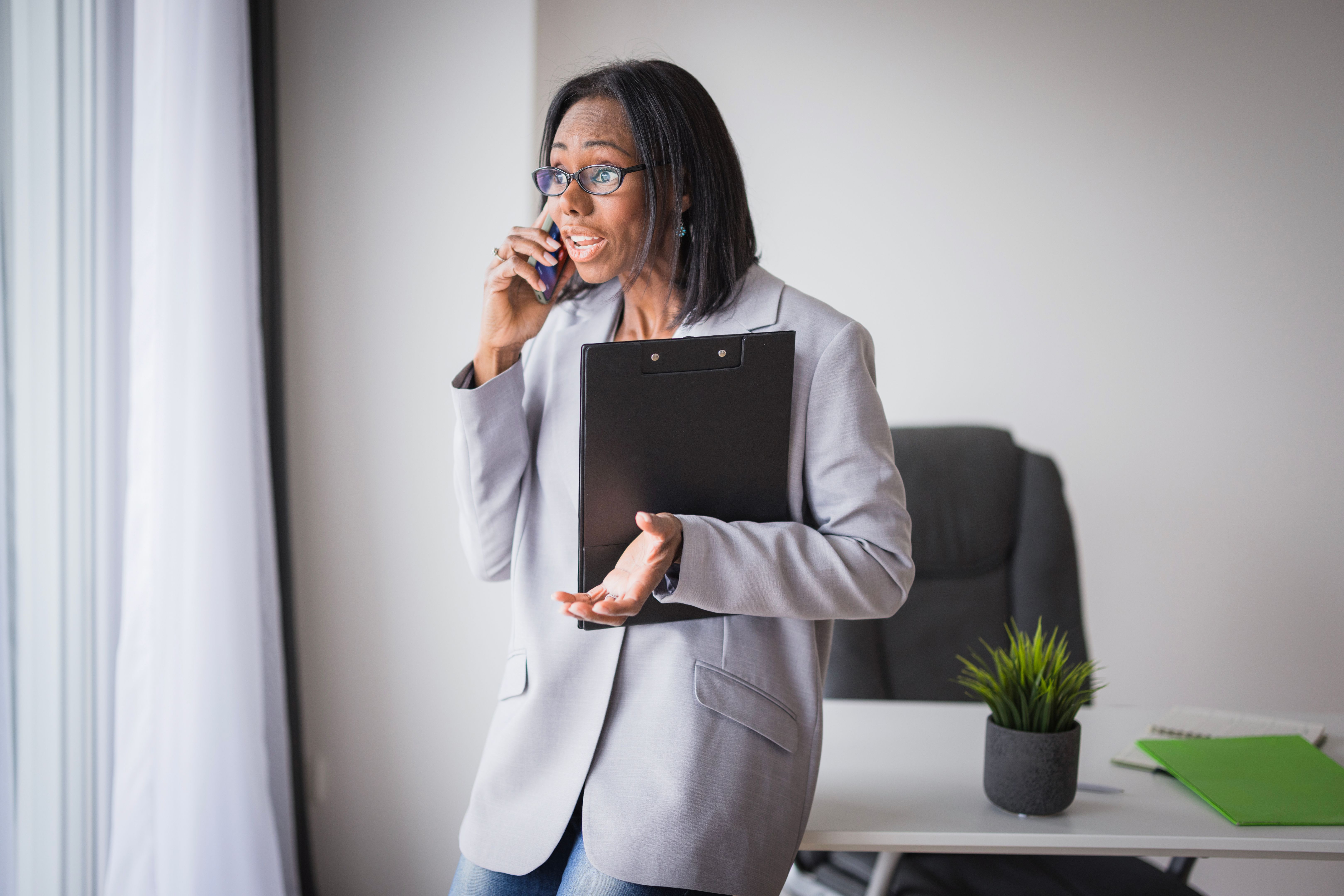 Displeased business woman with documents having a phone conversation