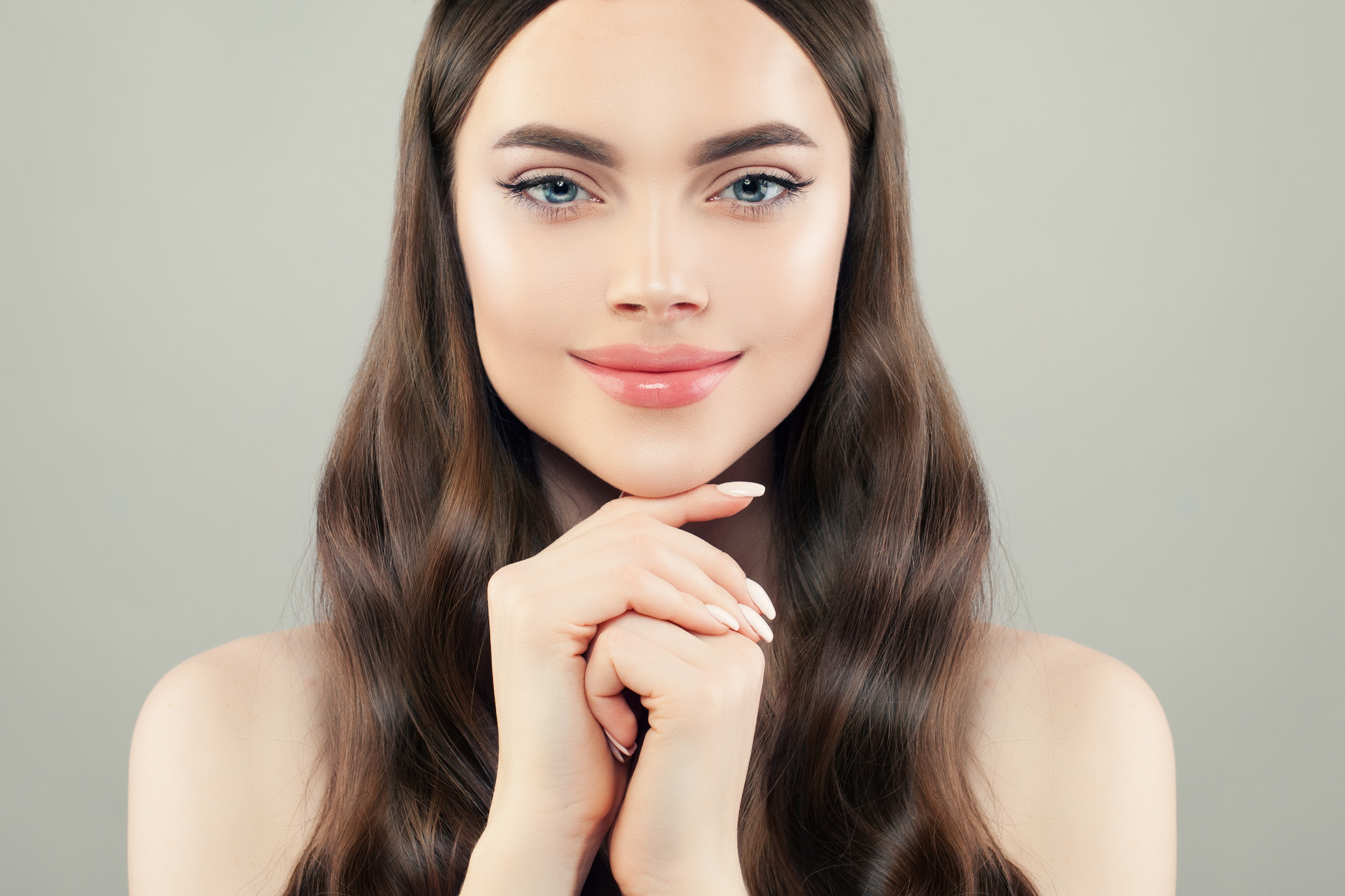 Pretty woman spa model with clear healthy skin, long hair and manicured nails closeup portrait