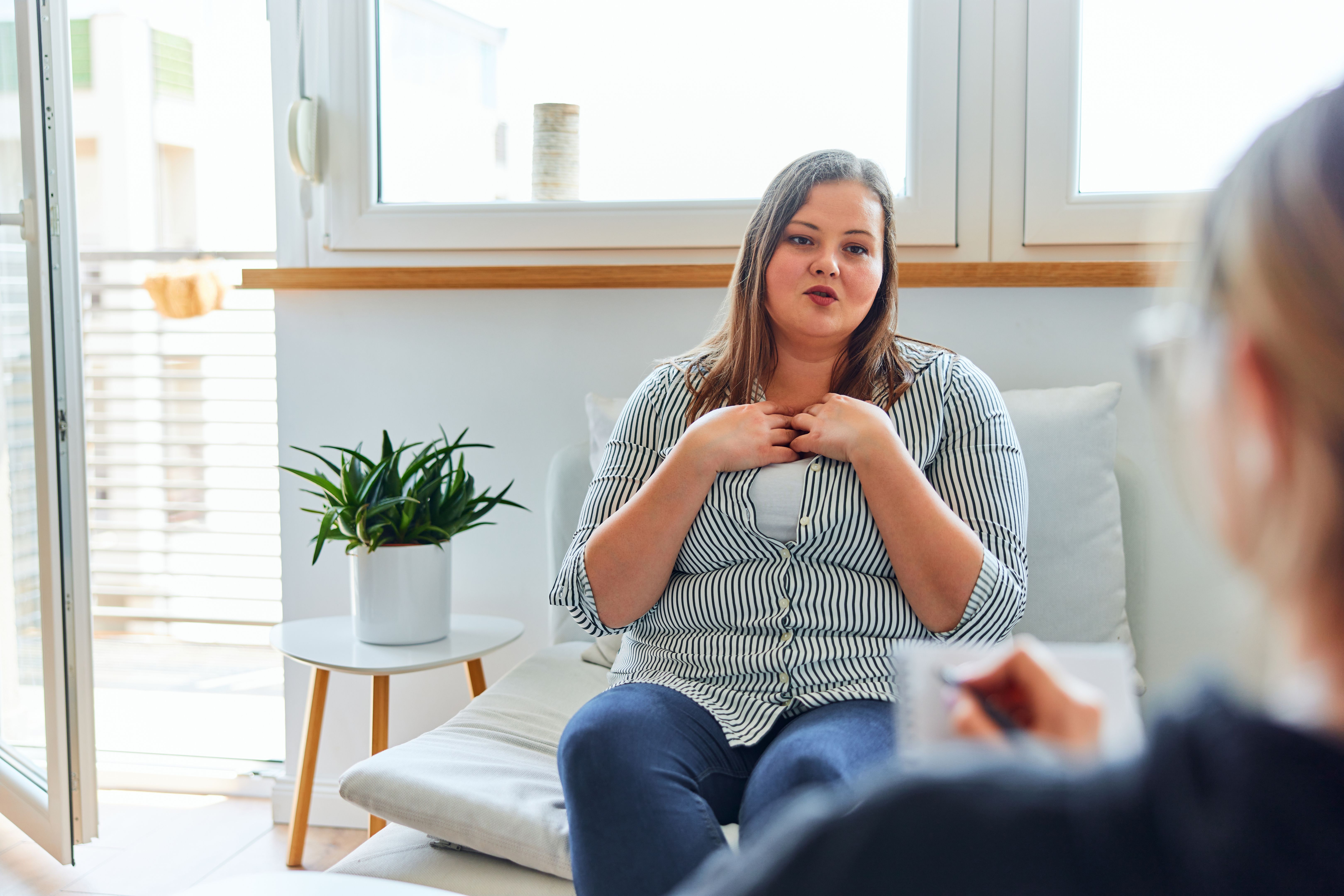 An overweight woman explains her problem to a female psychologist with a notebook. An overweight woman explains her problem to a female psychologist with a notebook.