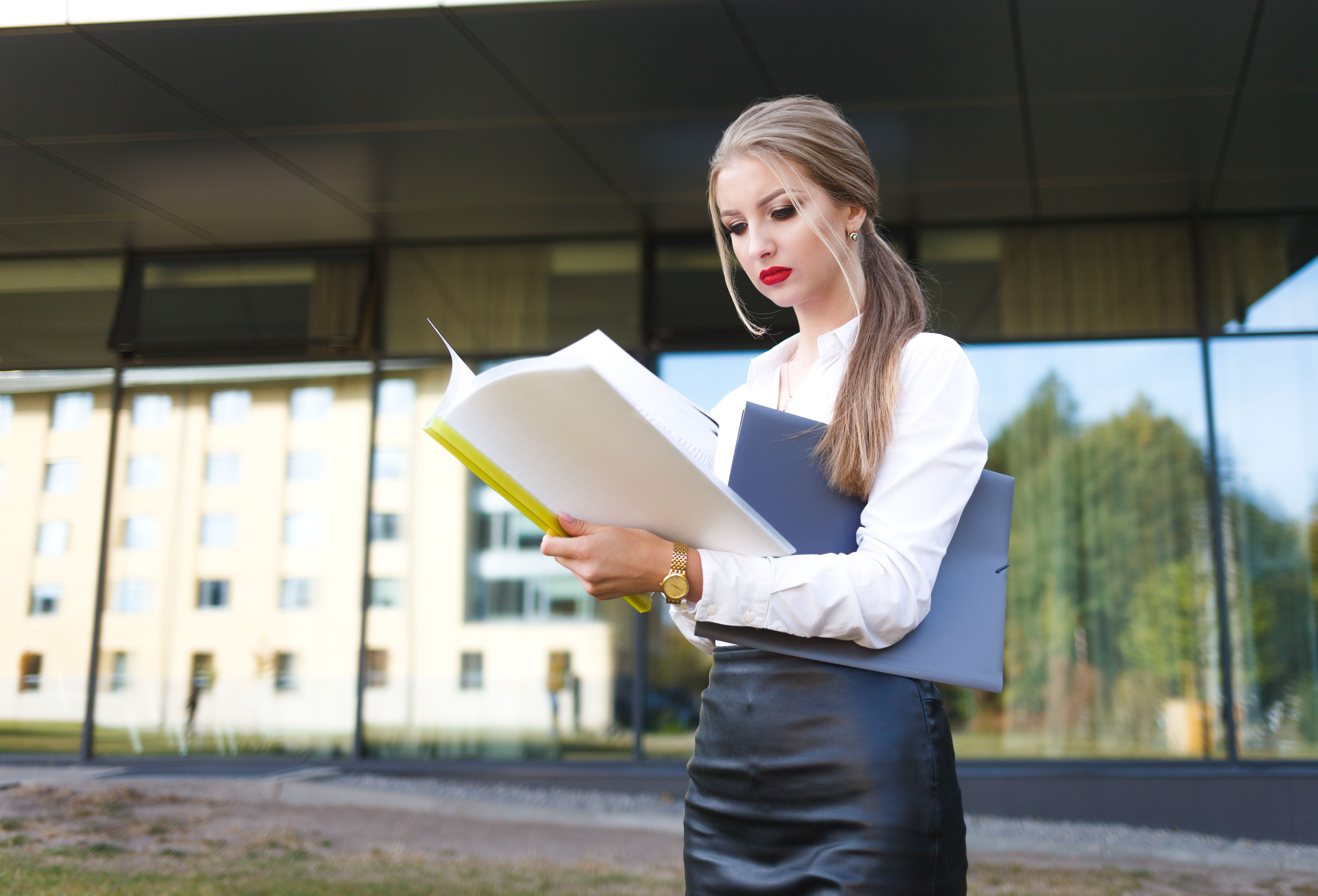 Young business woman with a displeased facial expression examines documents in detail Young business woman with a displeased facial expression examines documents in detail