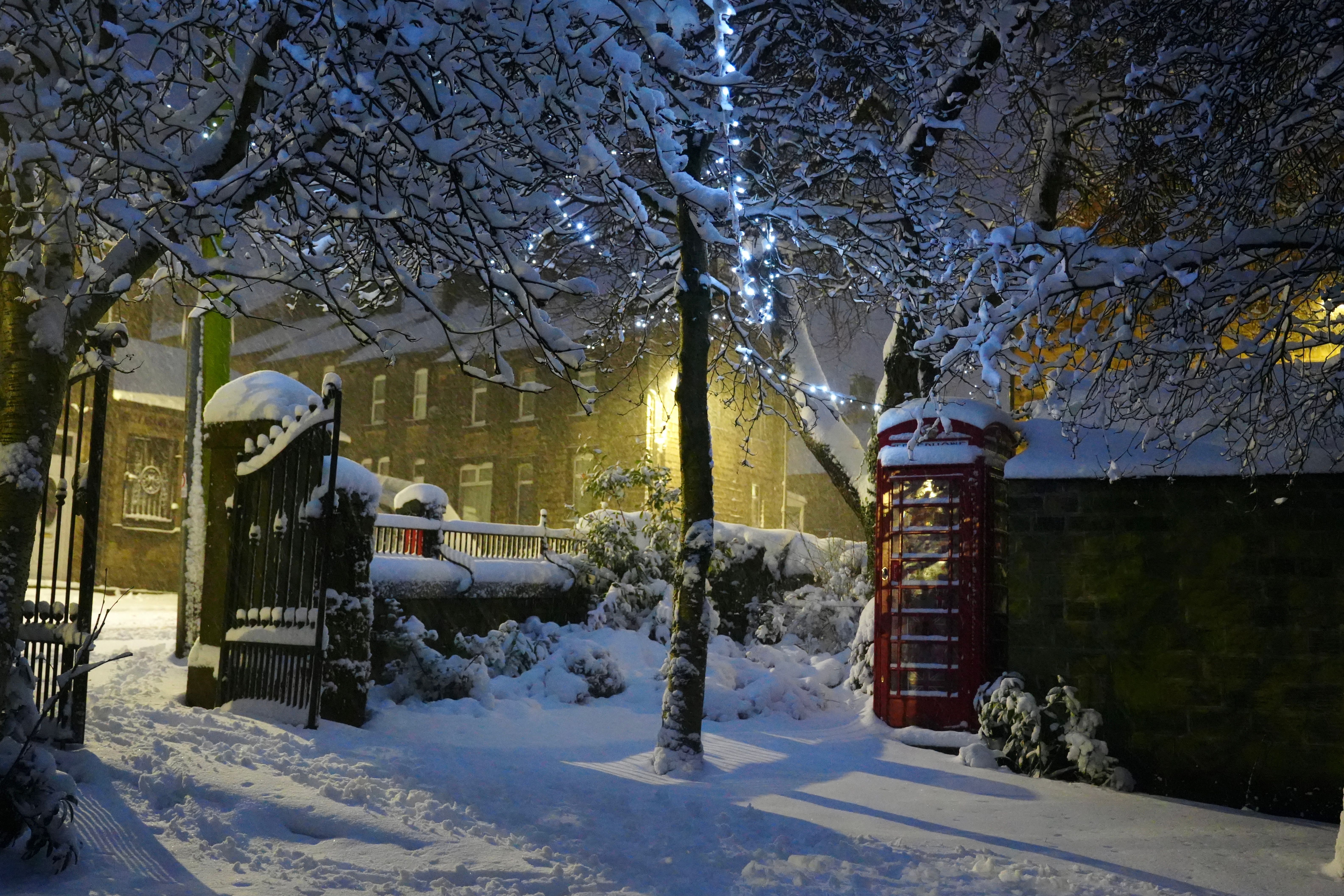 Snow village scene park gates with red telephone box/booth and Christmas lights North Yorkshire