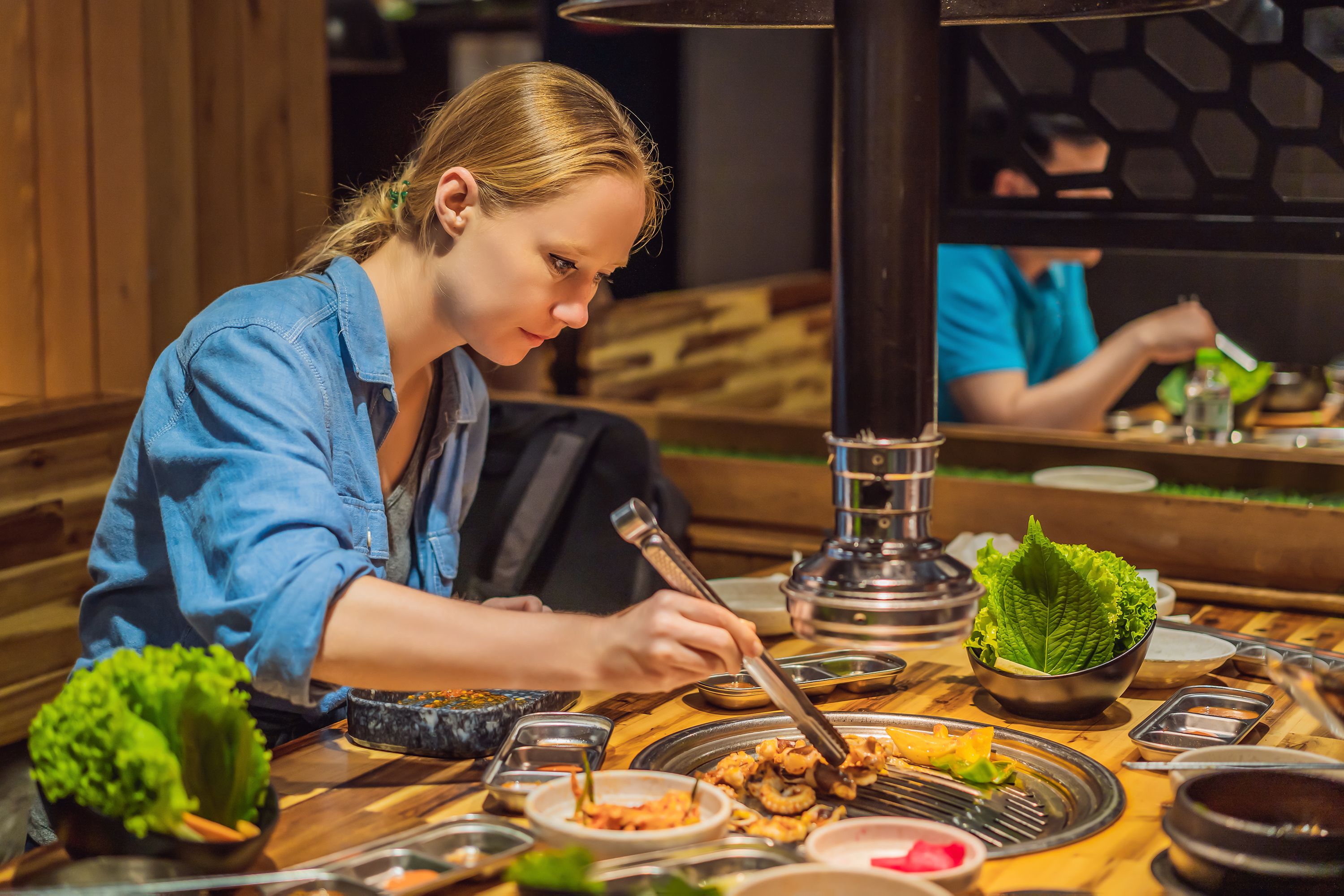 Woman grilling barbecue on mesh grill of charcoal fire. Korean or japanese traditional food grilling style barbecue Woman grilling barbecue on mesh grill of charcoal fire. Korean or japanese traditional food grilling style barbecue