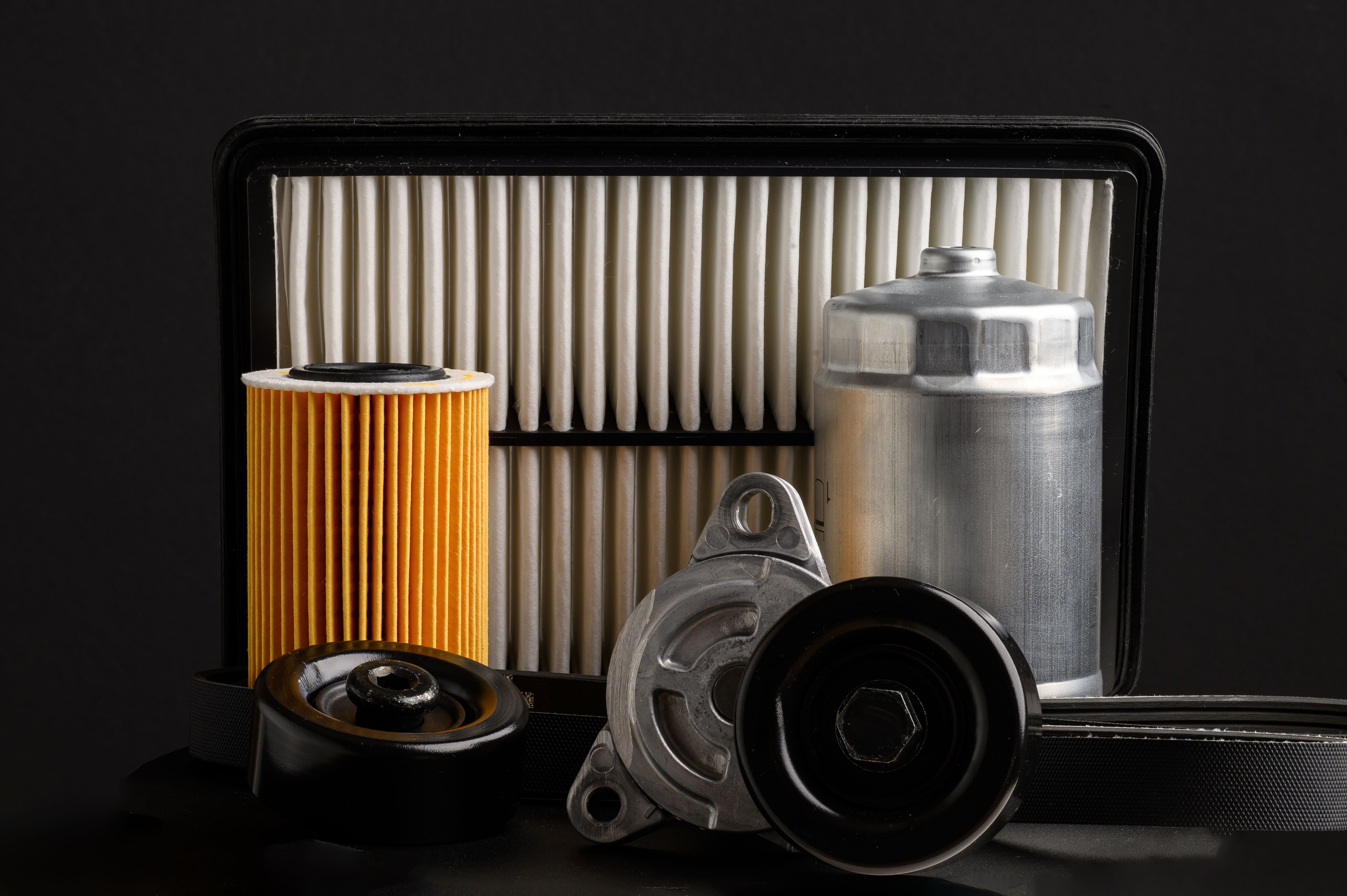 Auto parts car on a black background. Fuel, oil, air filters and tension and guide rollers, poly V-belt, close-up. Replacement of auto parts.