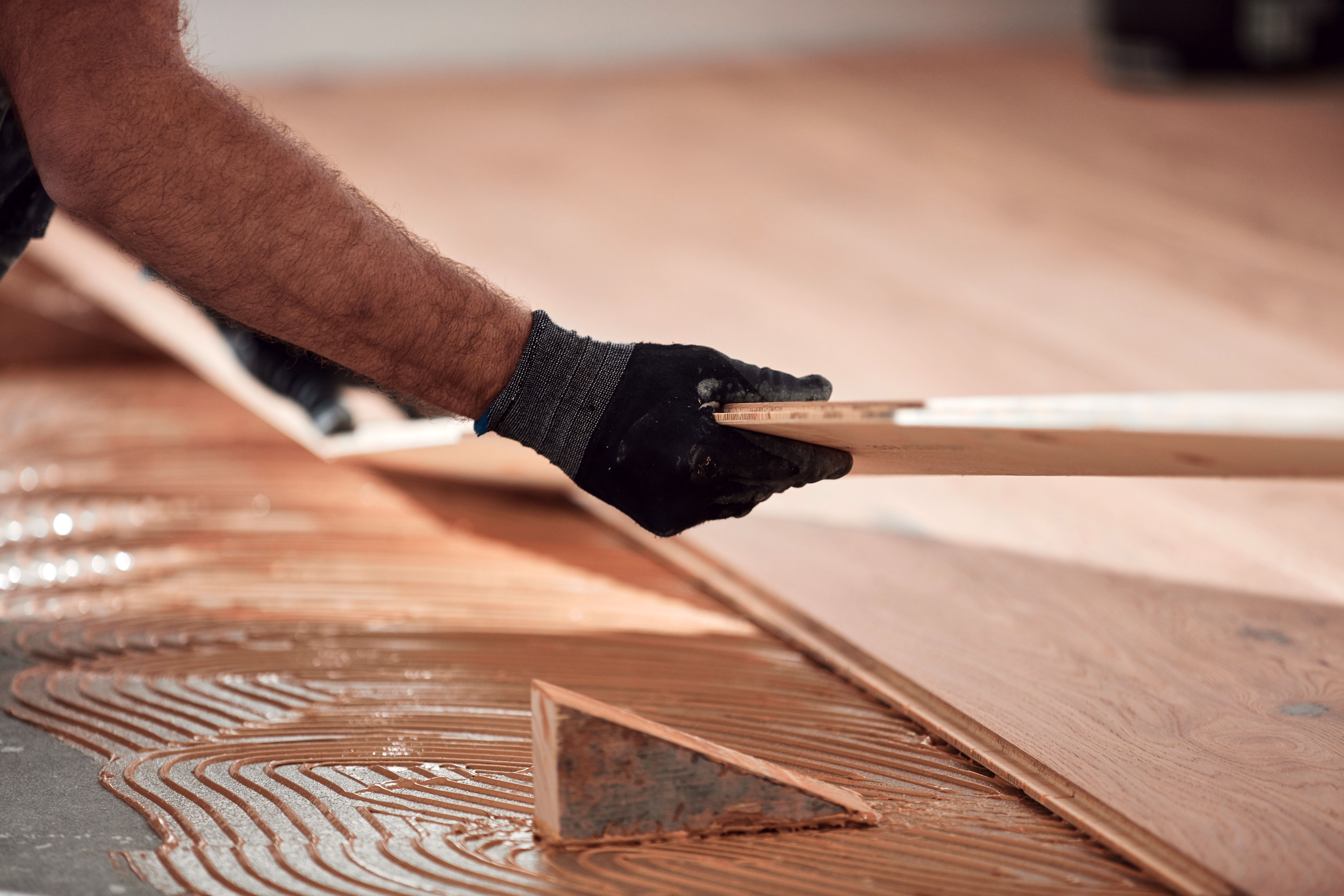 Professional handyman installing laminate flooring in a new apartment.