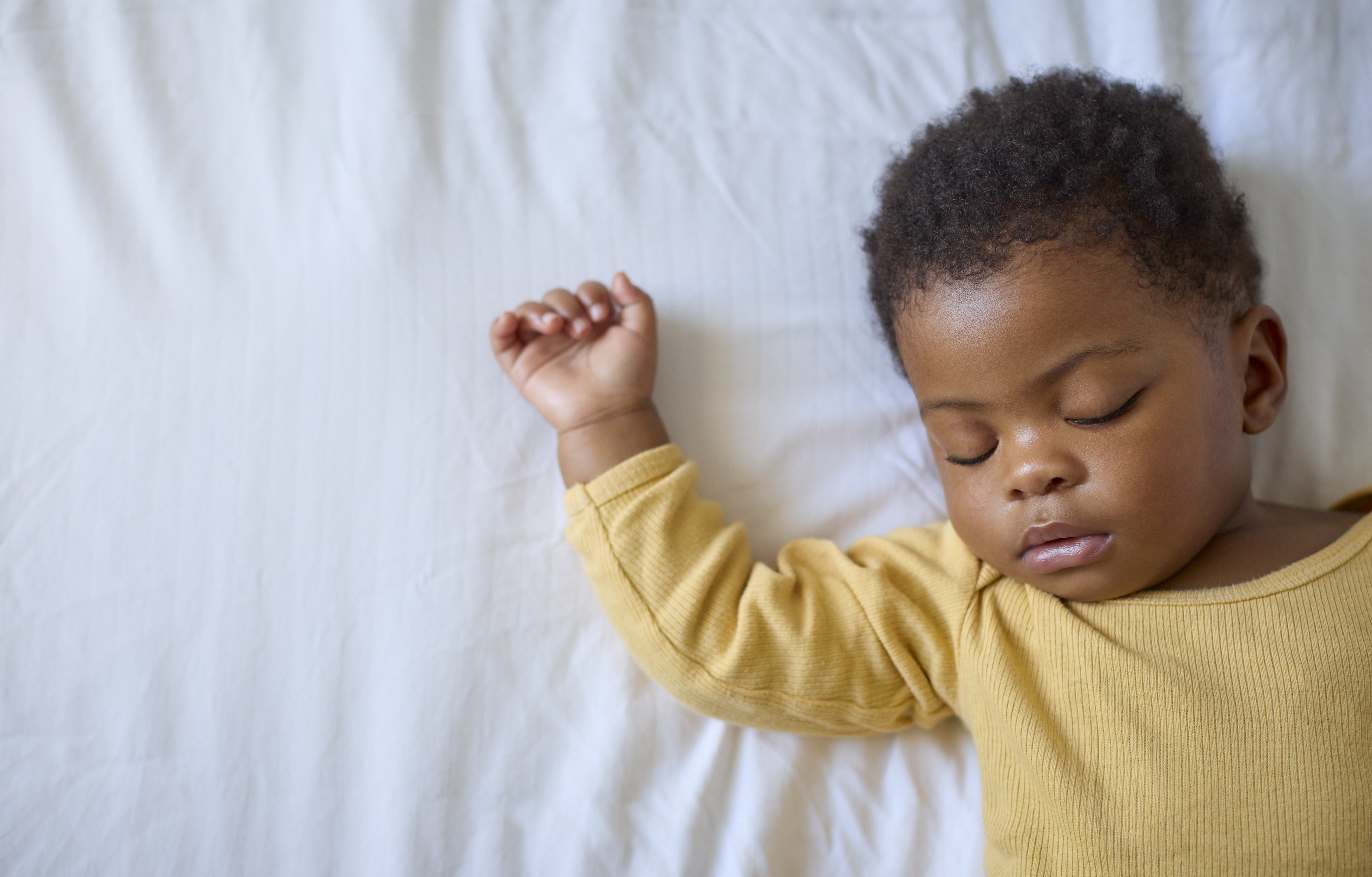 Close Up Of Sleeping Baby Girl Lying On Parent's Bed At Home