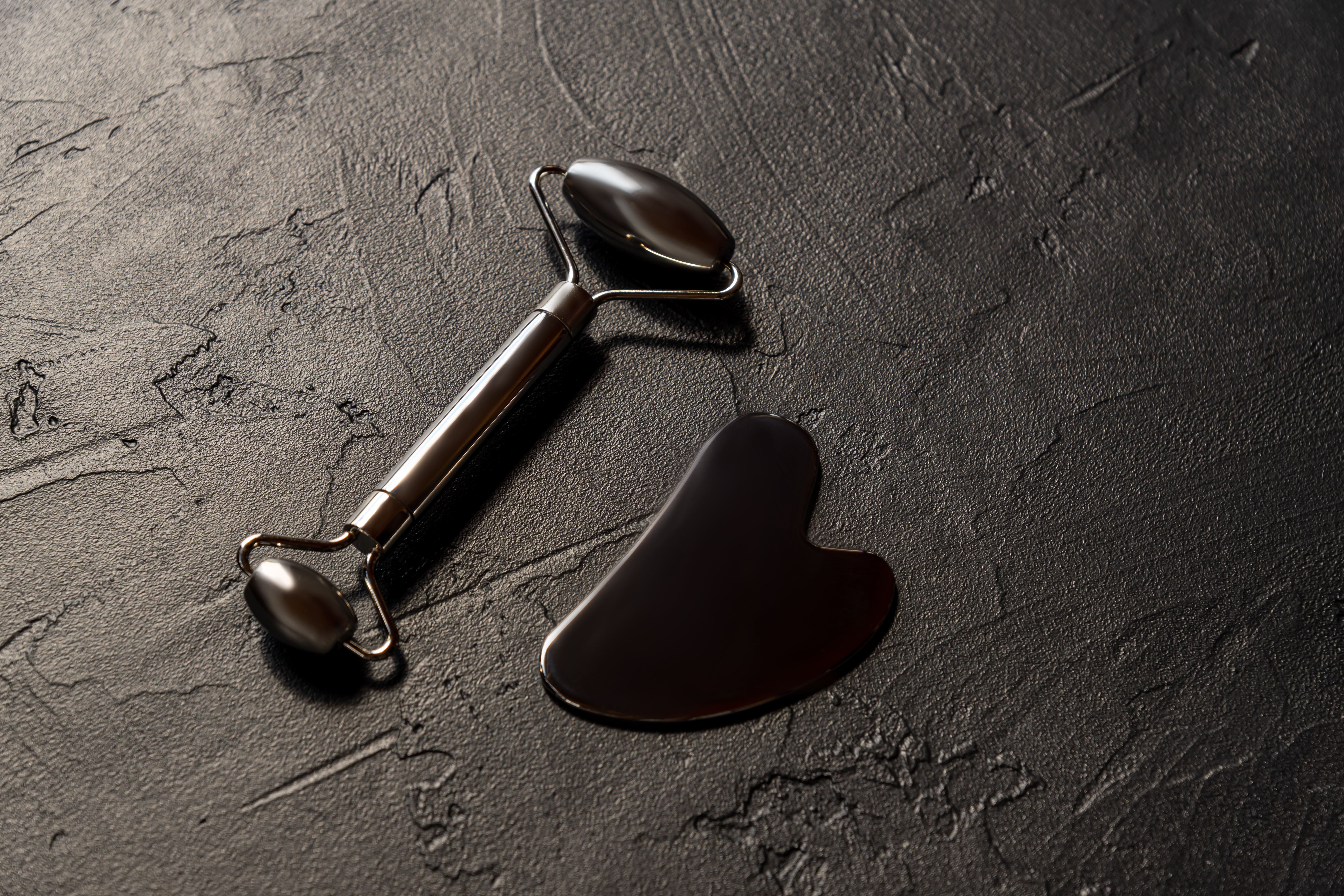 Self-care set layout. Face roller, massager guasha scraper made of surgical steel. Flat lay. space for text. Concept of alternative medicine treatment. Chineese acupuntur massage