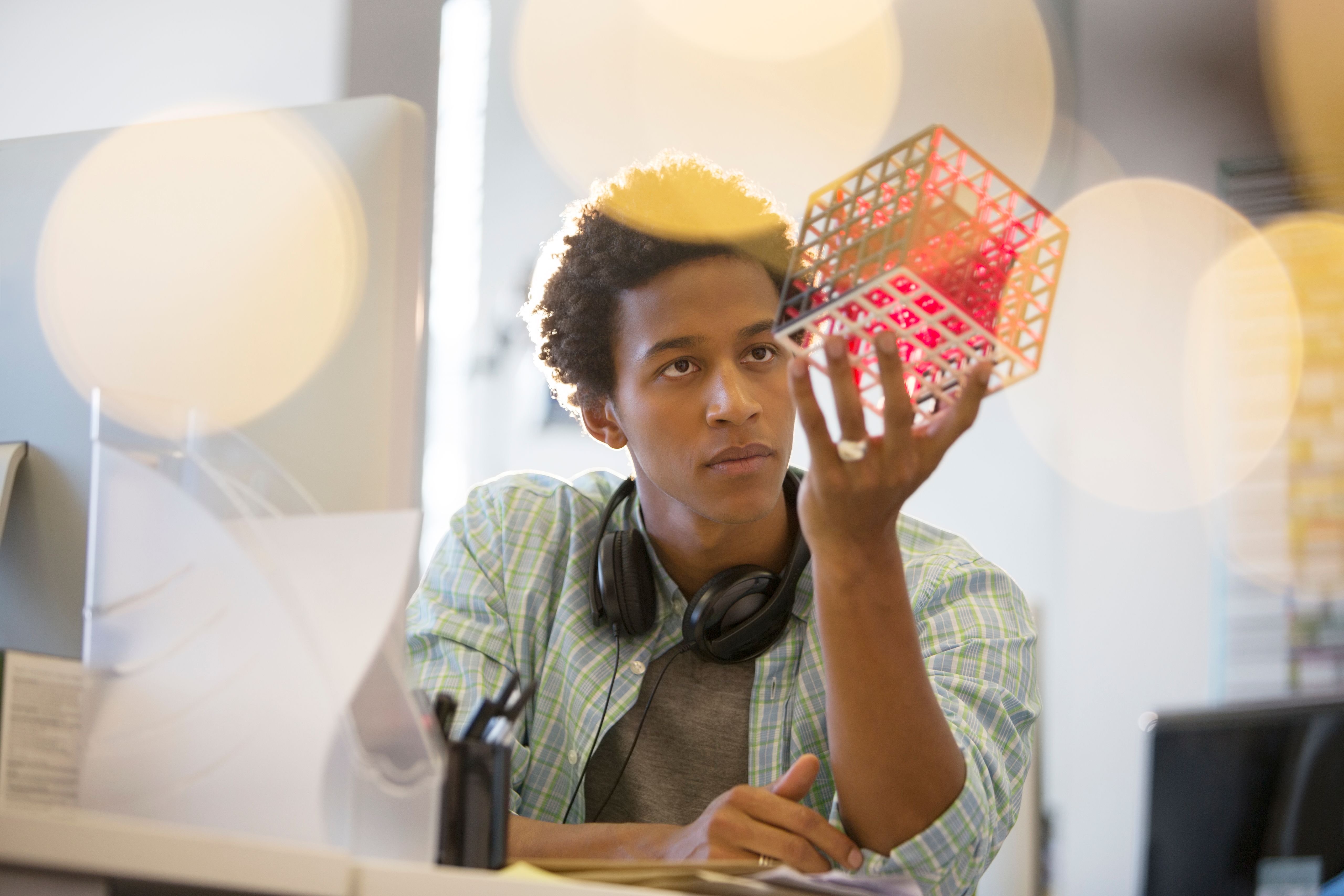 Businessman examining cube at desk in office Businessman examining cube at desk in office