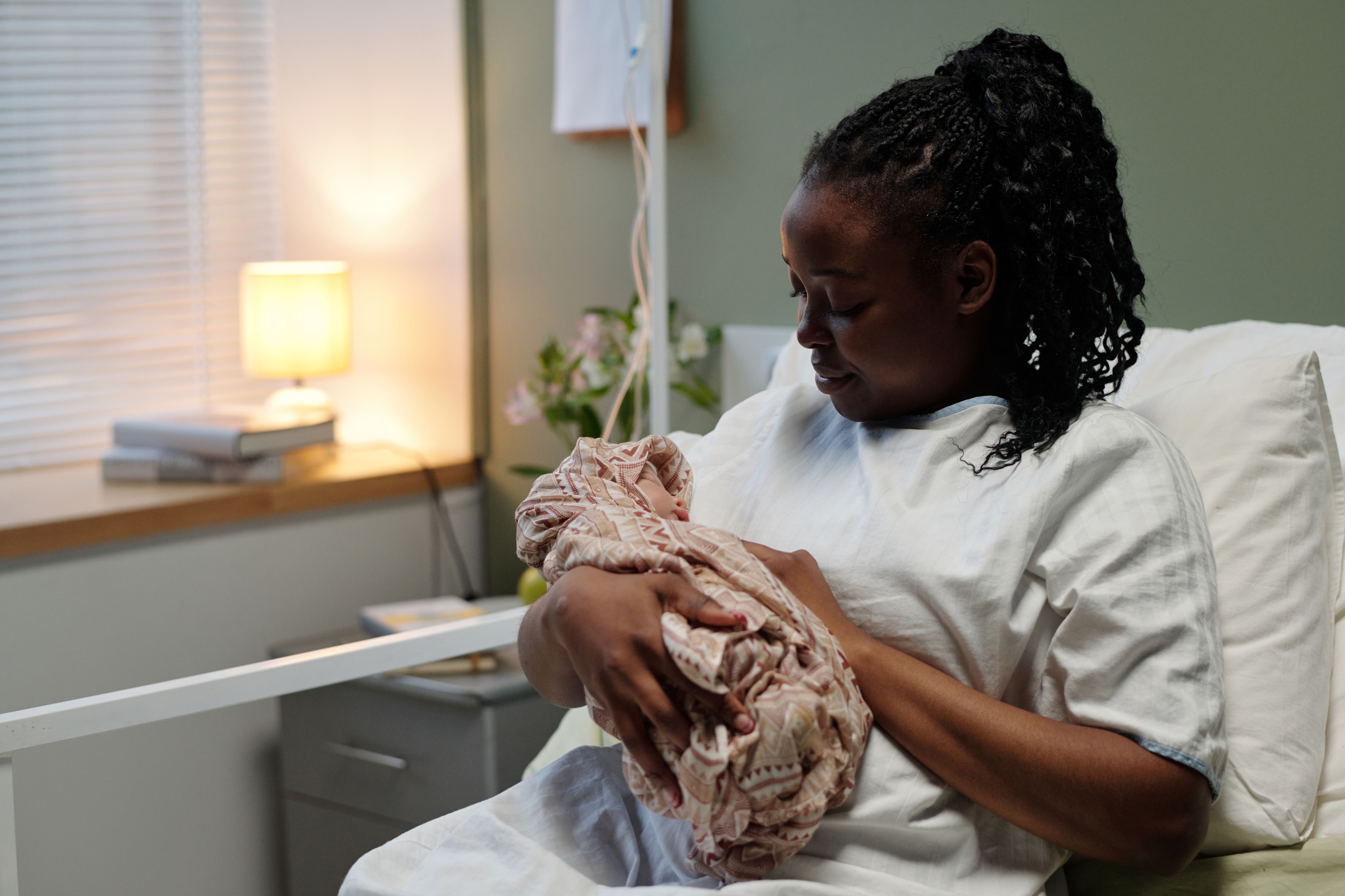 Black mother cradling newborn in hospital