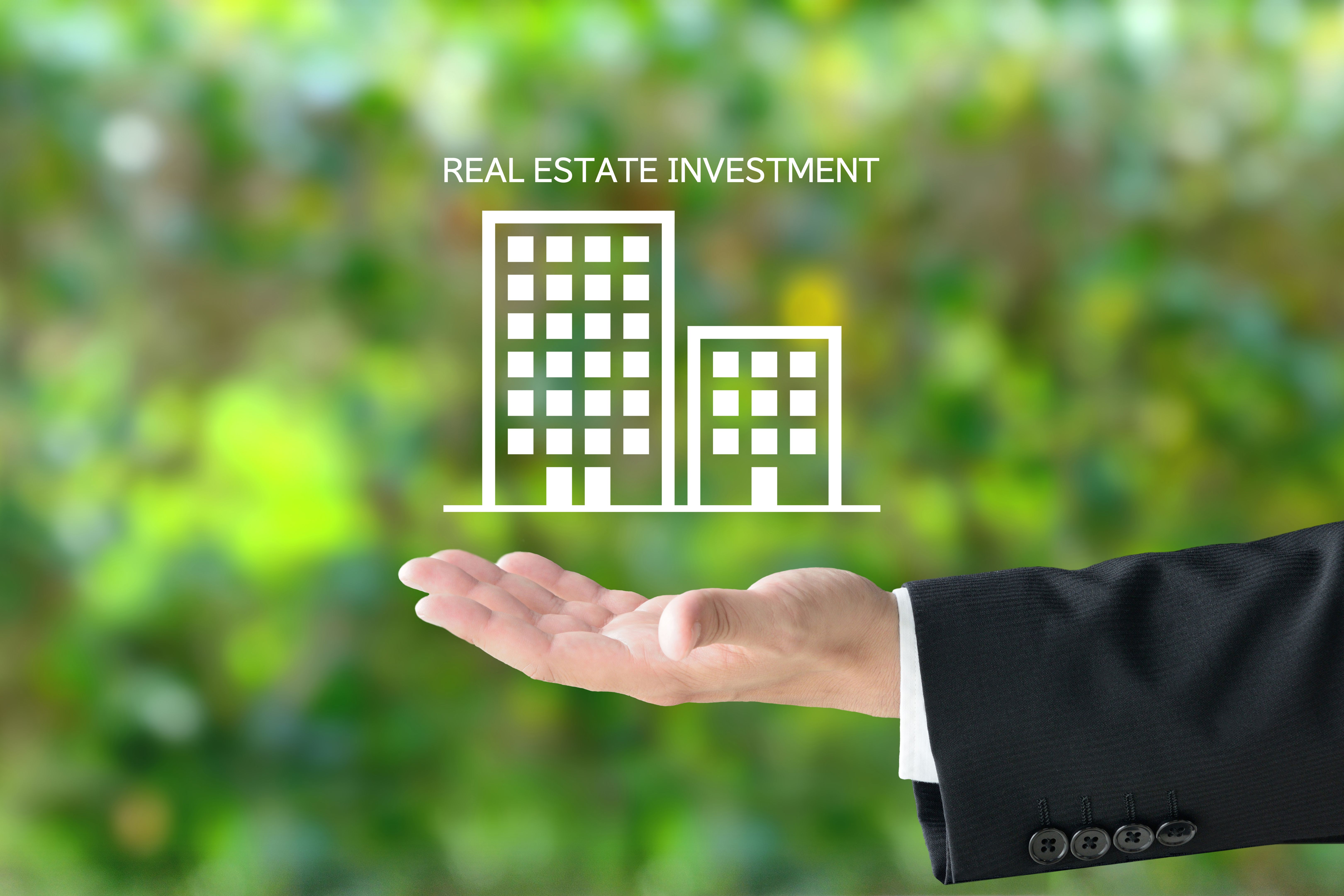 Business man's hand and building pictogram with REAL ESTATE INVESTMENT word Business man's hand and building pictogram with REAL ESTATE INVESTMENT word