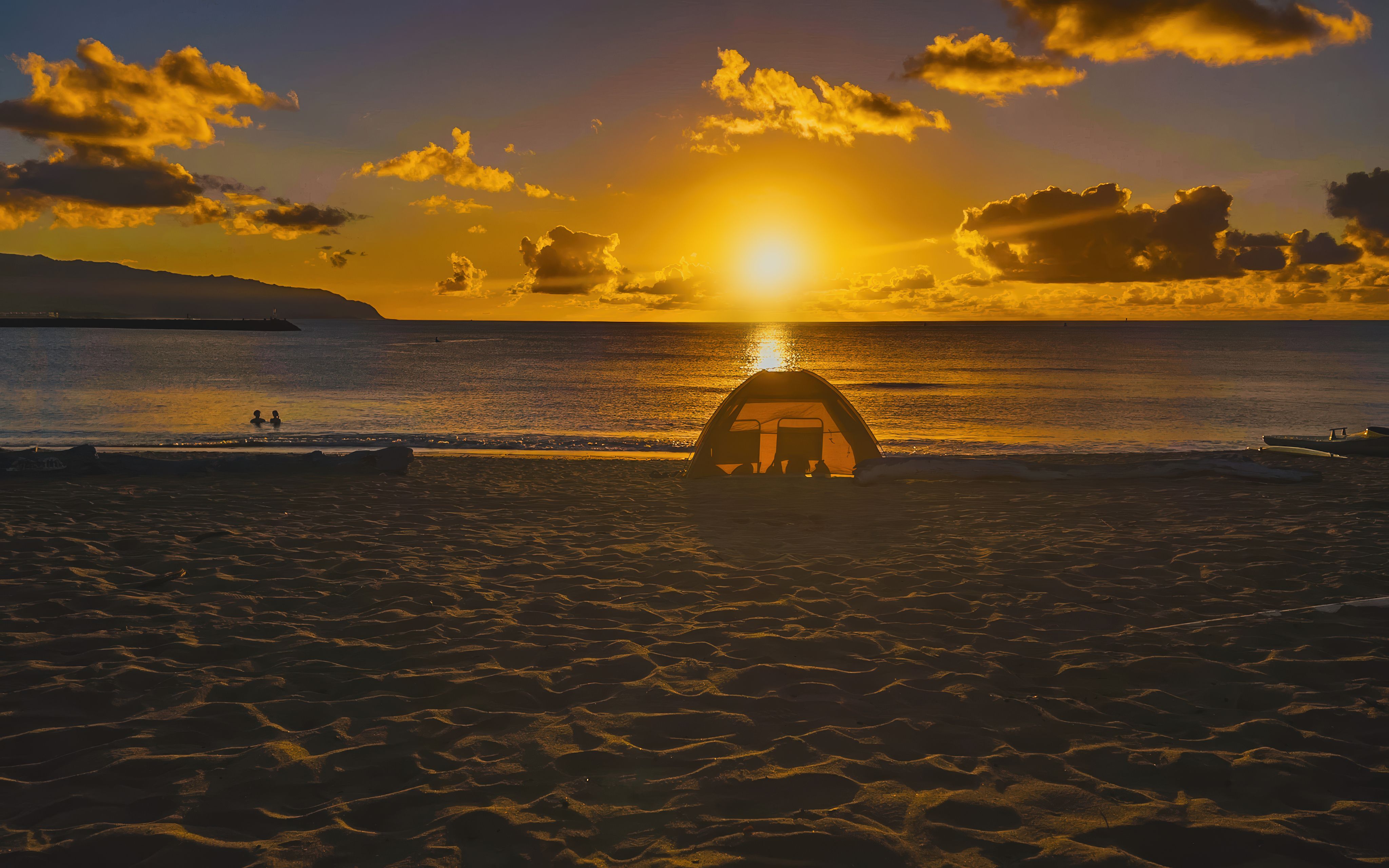 A serene sunset at the beach with golden hour and silhouette and dramatic sky with a few clouds.
