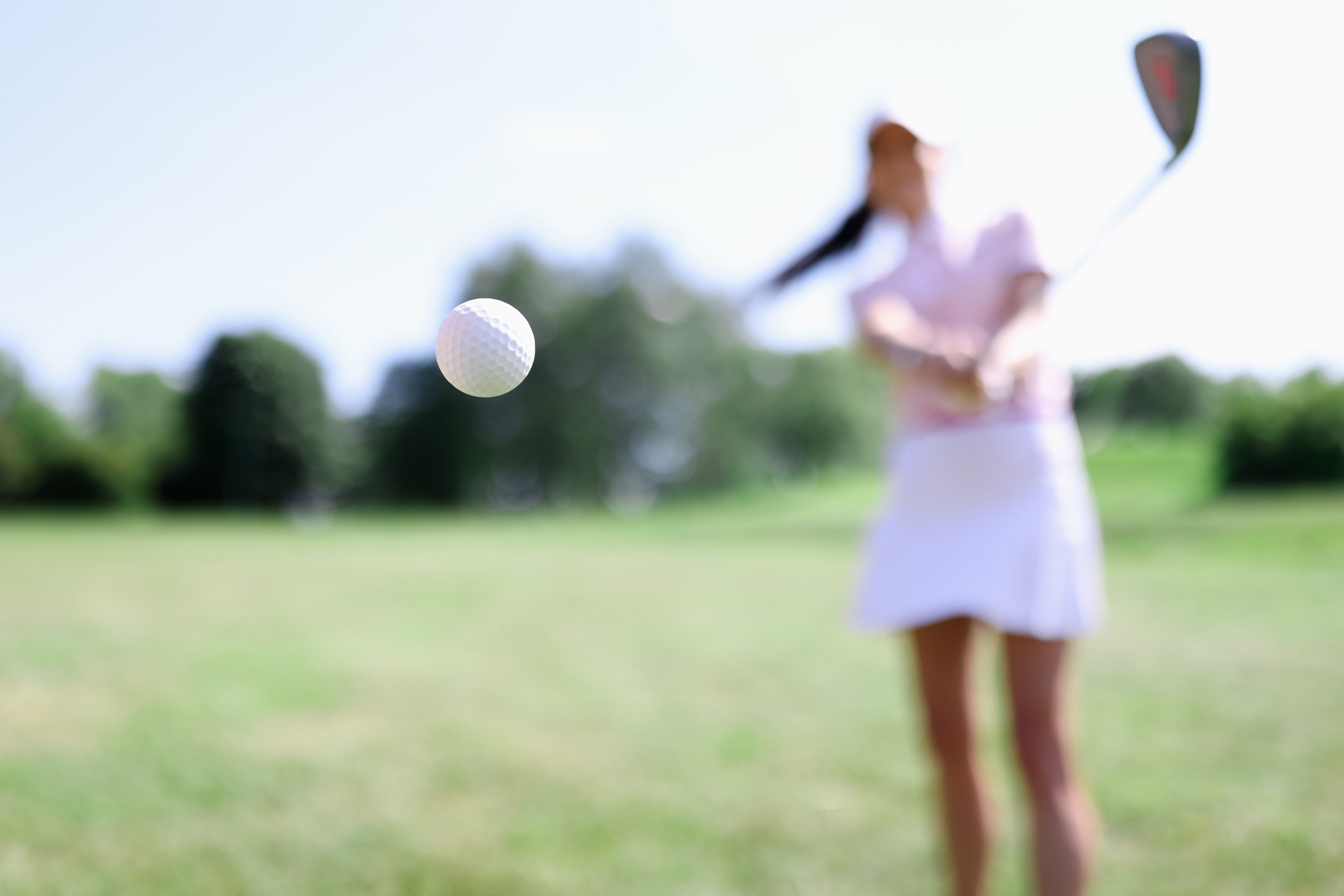 Golf ball against background of hitting woman closeup Golf ball against background of hitting woman closeup