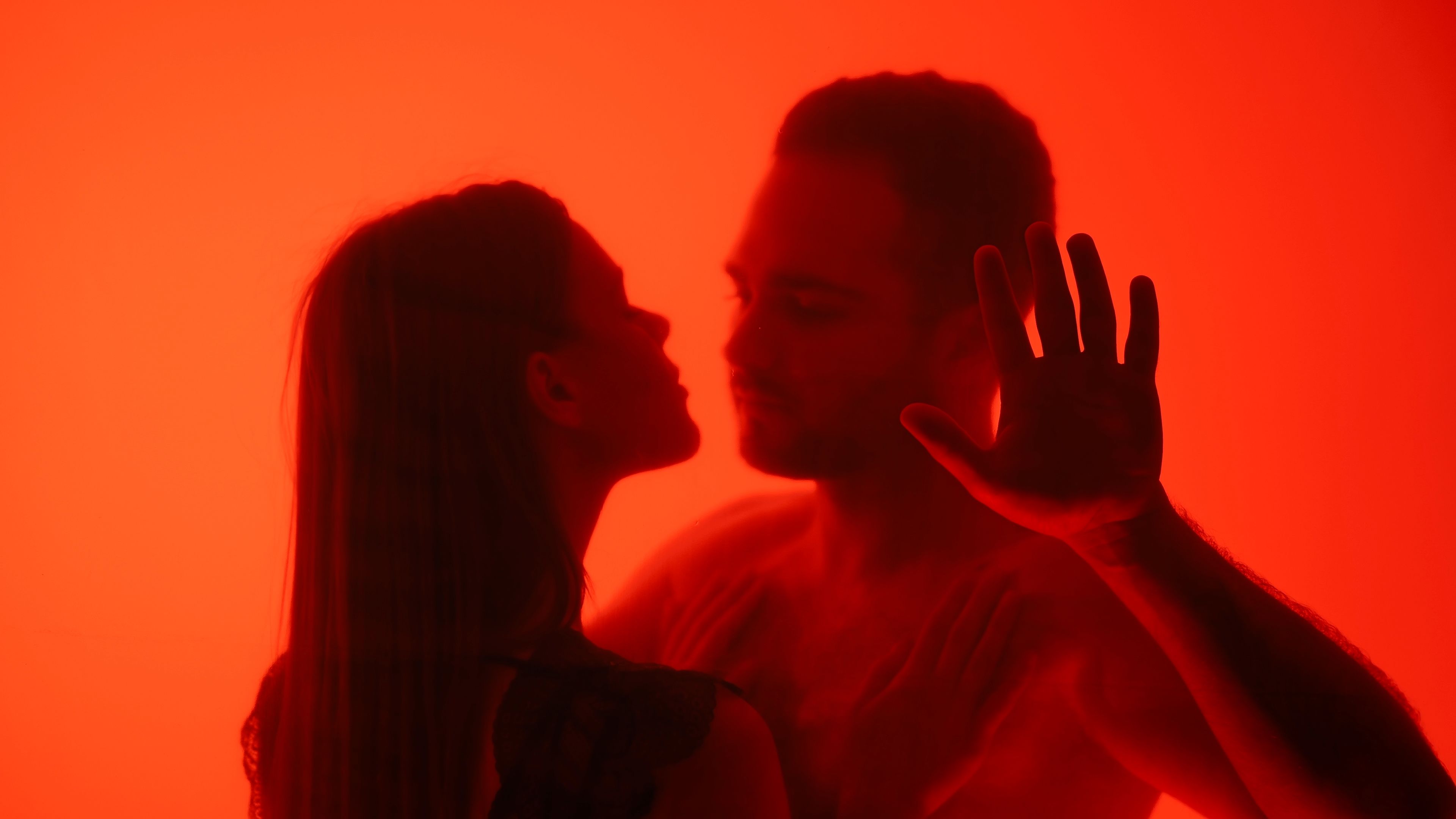 Silhouetted Couple Kissing Behind a Red Glass Surface