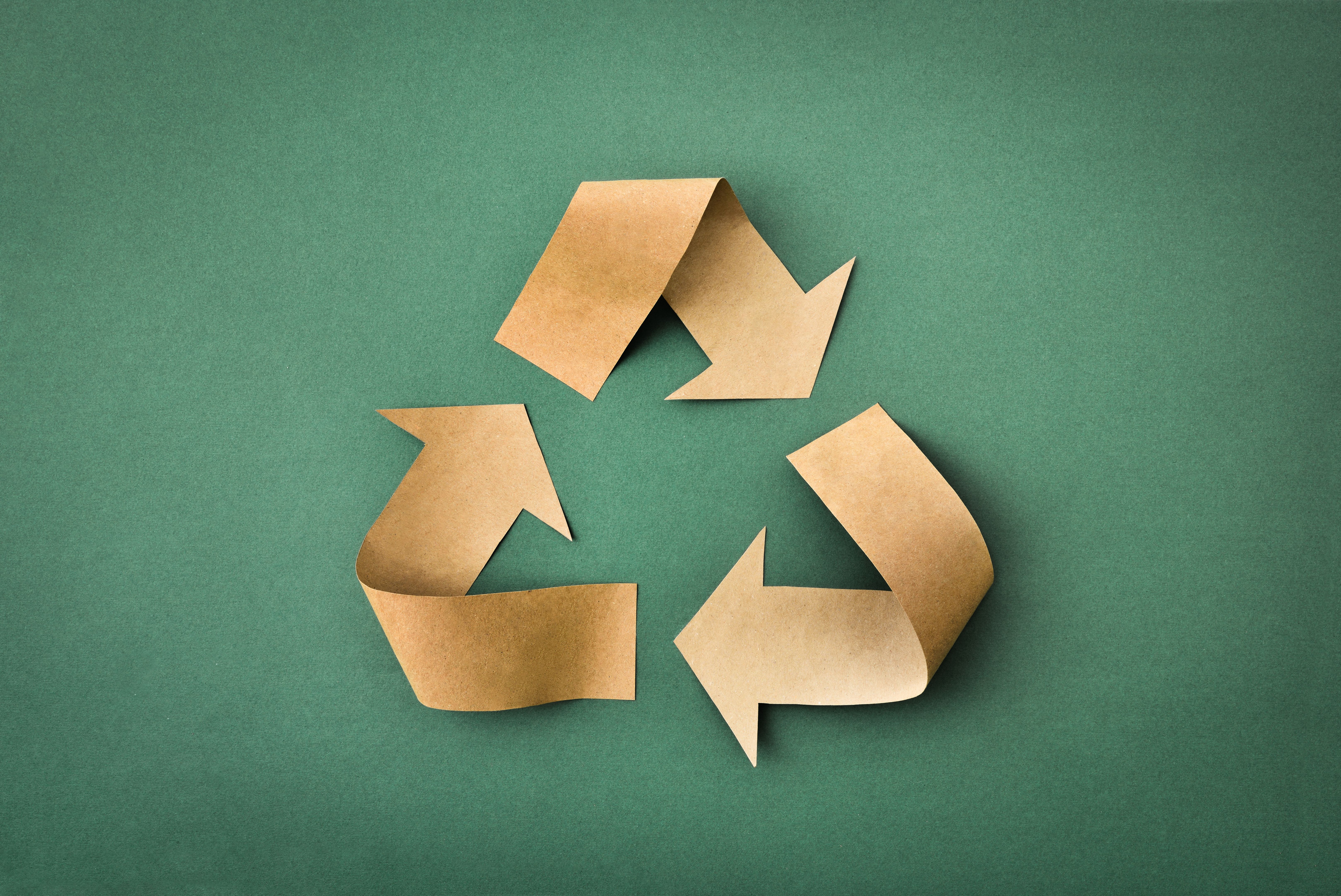 Recycling symbol made of brown paper on green textured background Recycling symbol made of brown paper on green textured background