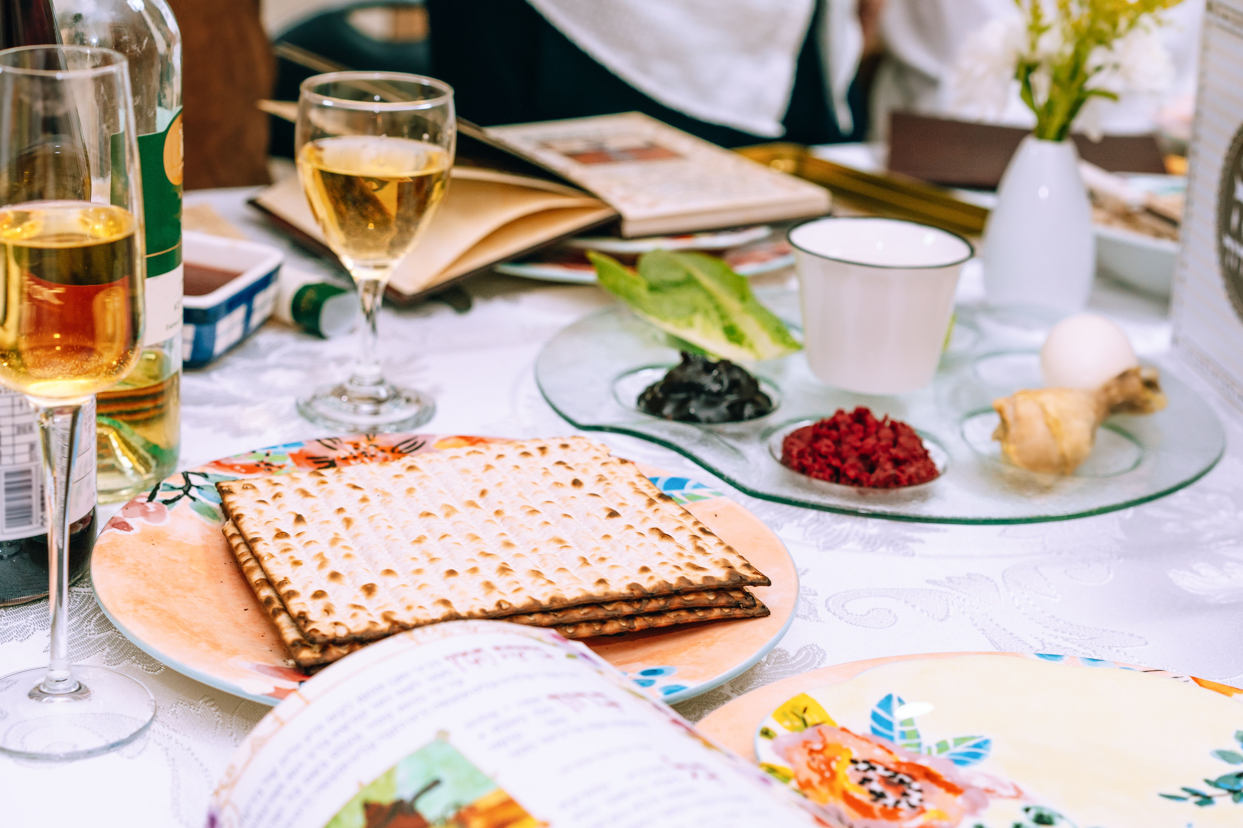 Table served for Passover Seder Pesach. Passover table setting with a traditional Passover seder plate with symbolic meal, matzah and Passover Haggadah.
