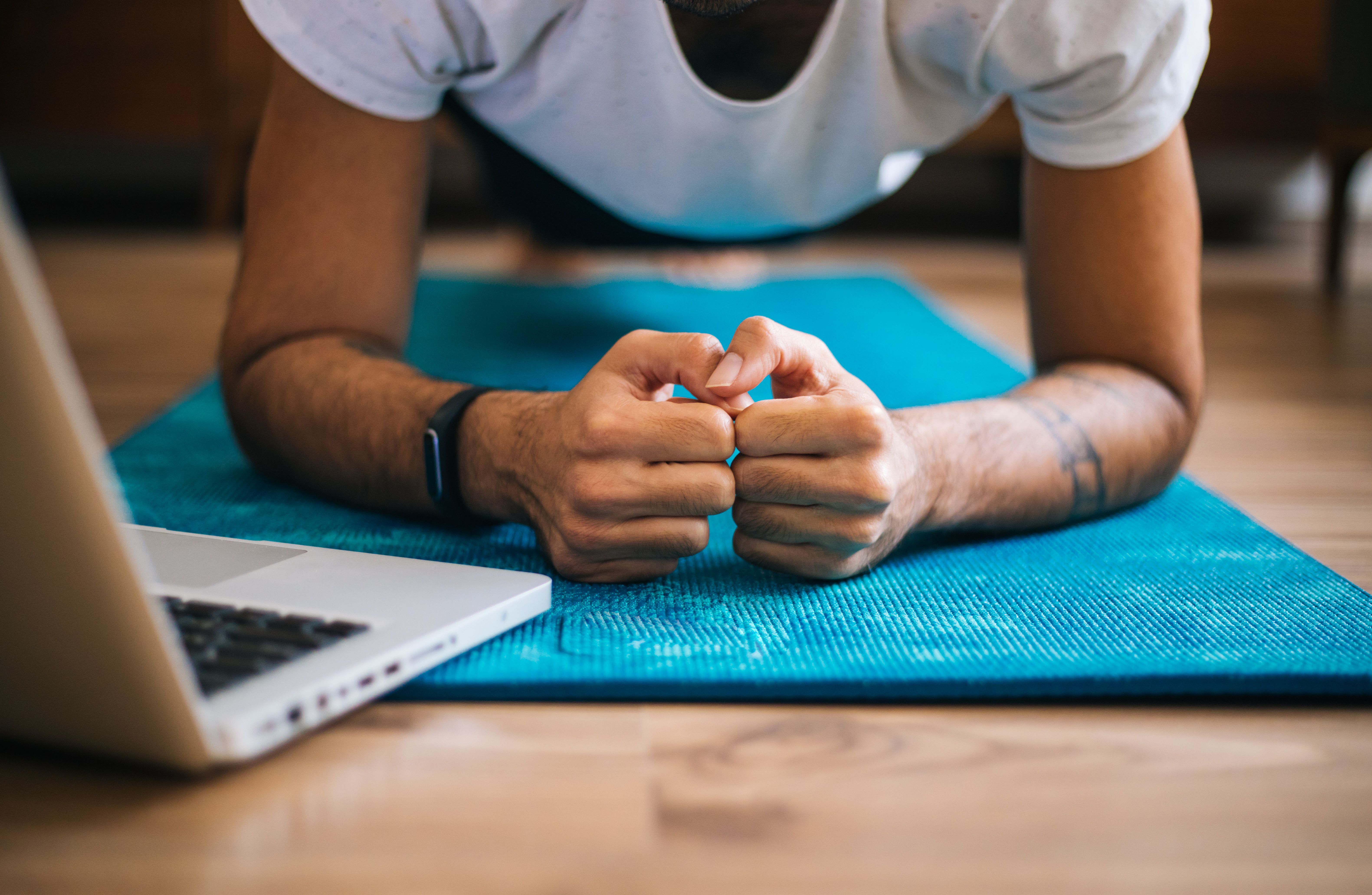 Man uses laptop to lean plank position