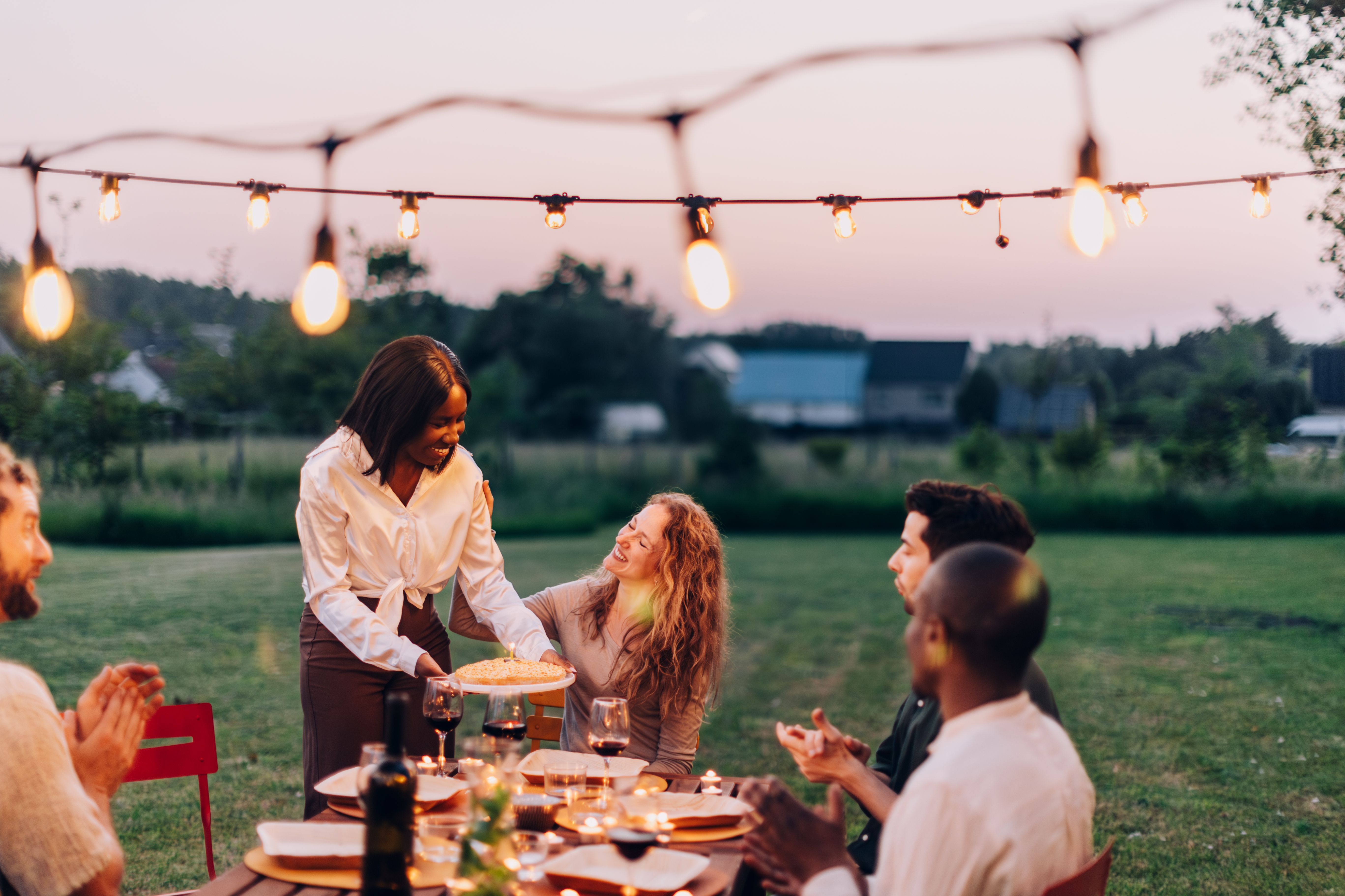 Friends enjoying a dinner party outdoors at sunset
