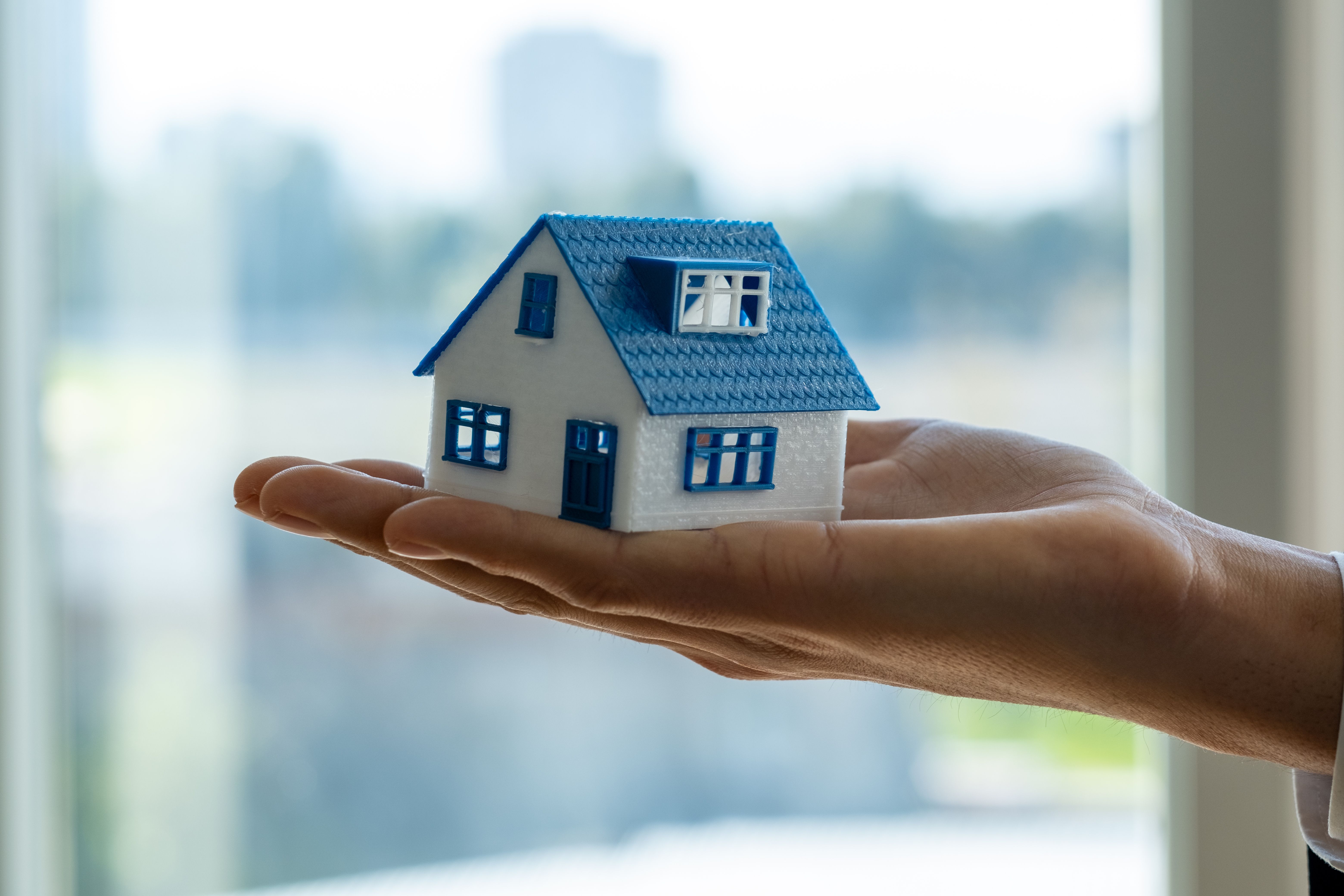 Agente imobiliário segurando o modelo de casa pequena na mão