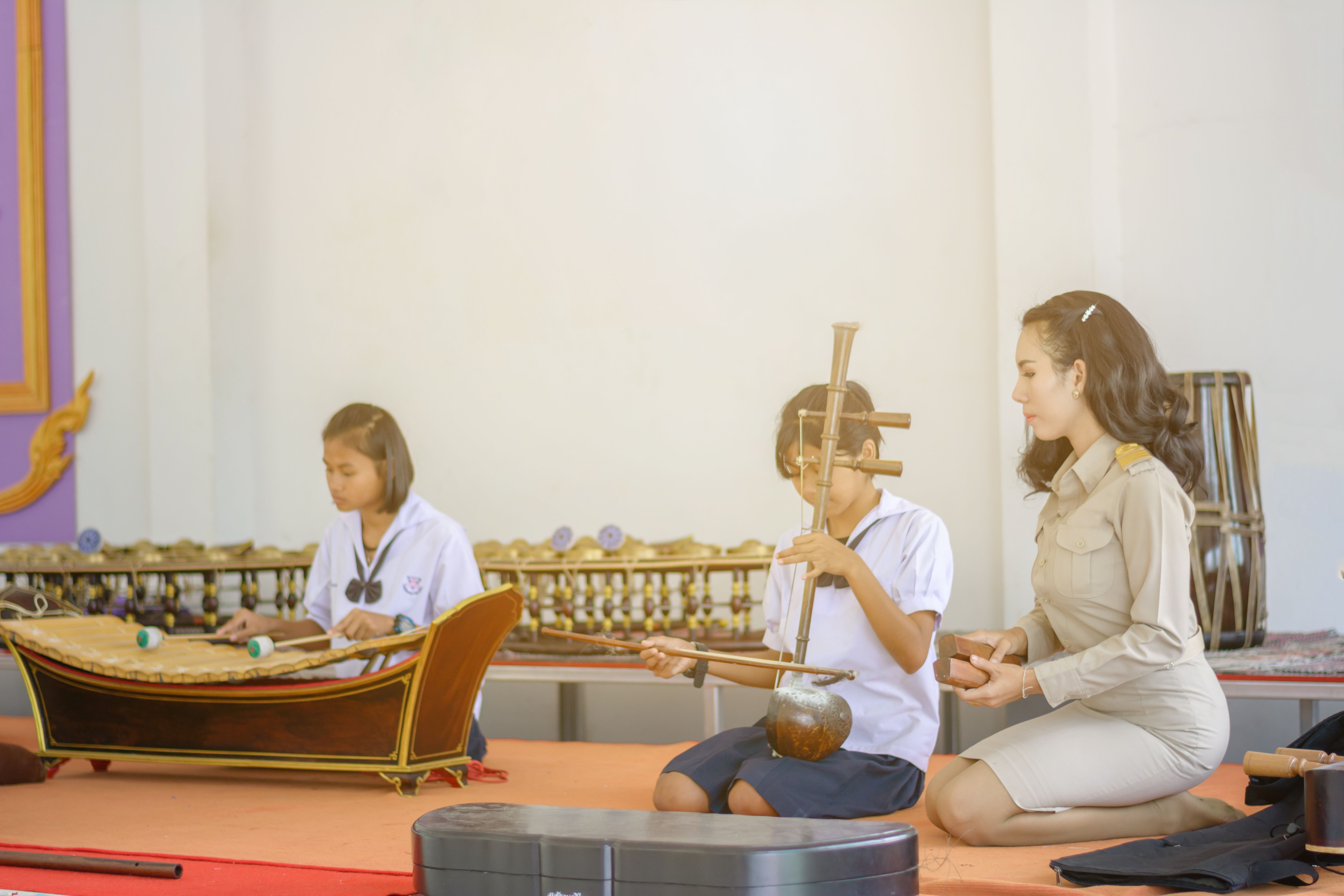 Beautiful Asian Teacher teaching students to practice Thai instruments