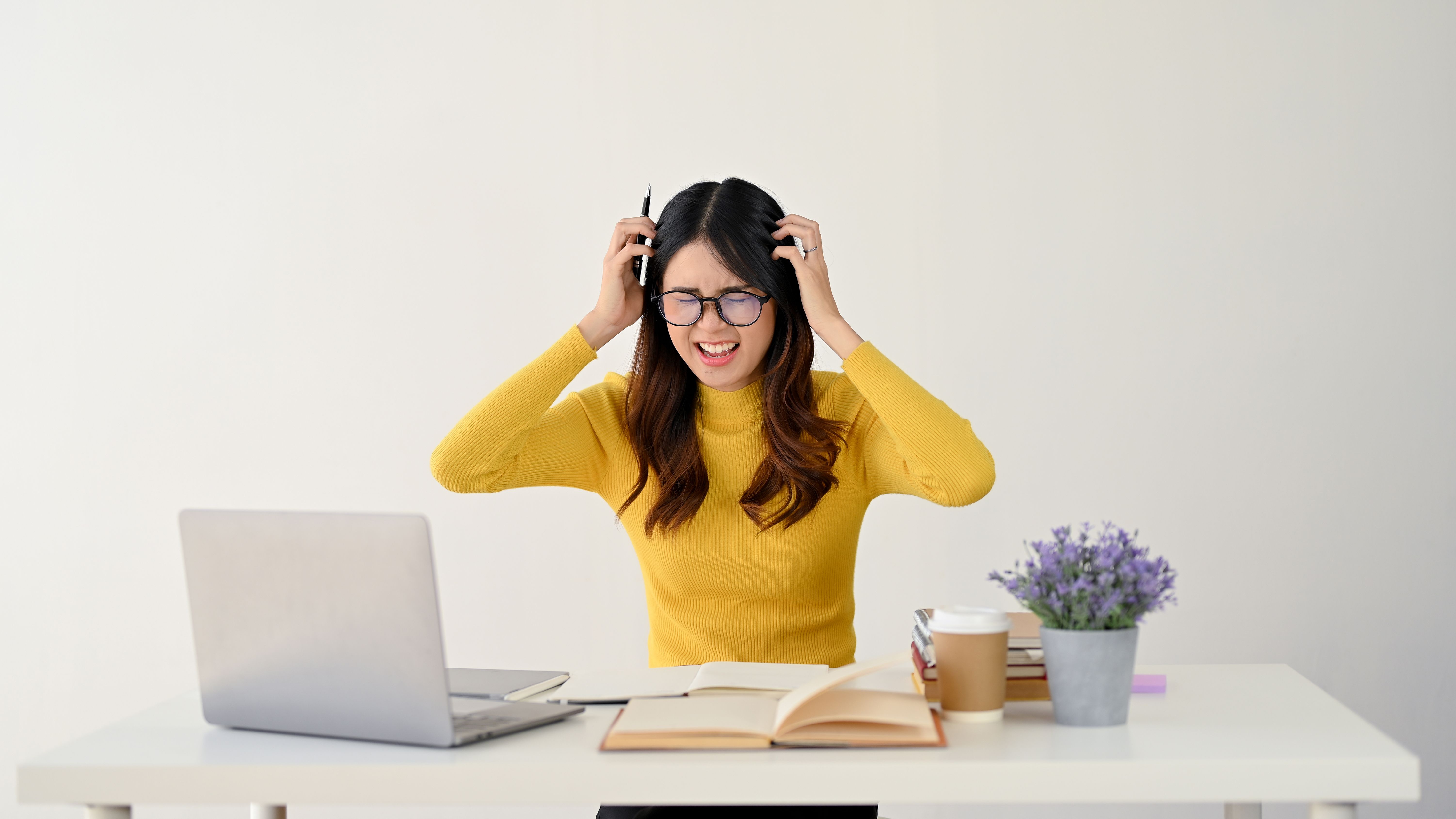 A furious female college student is pulling her hair with anger while working on a hard project