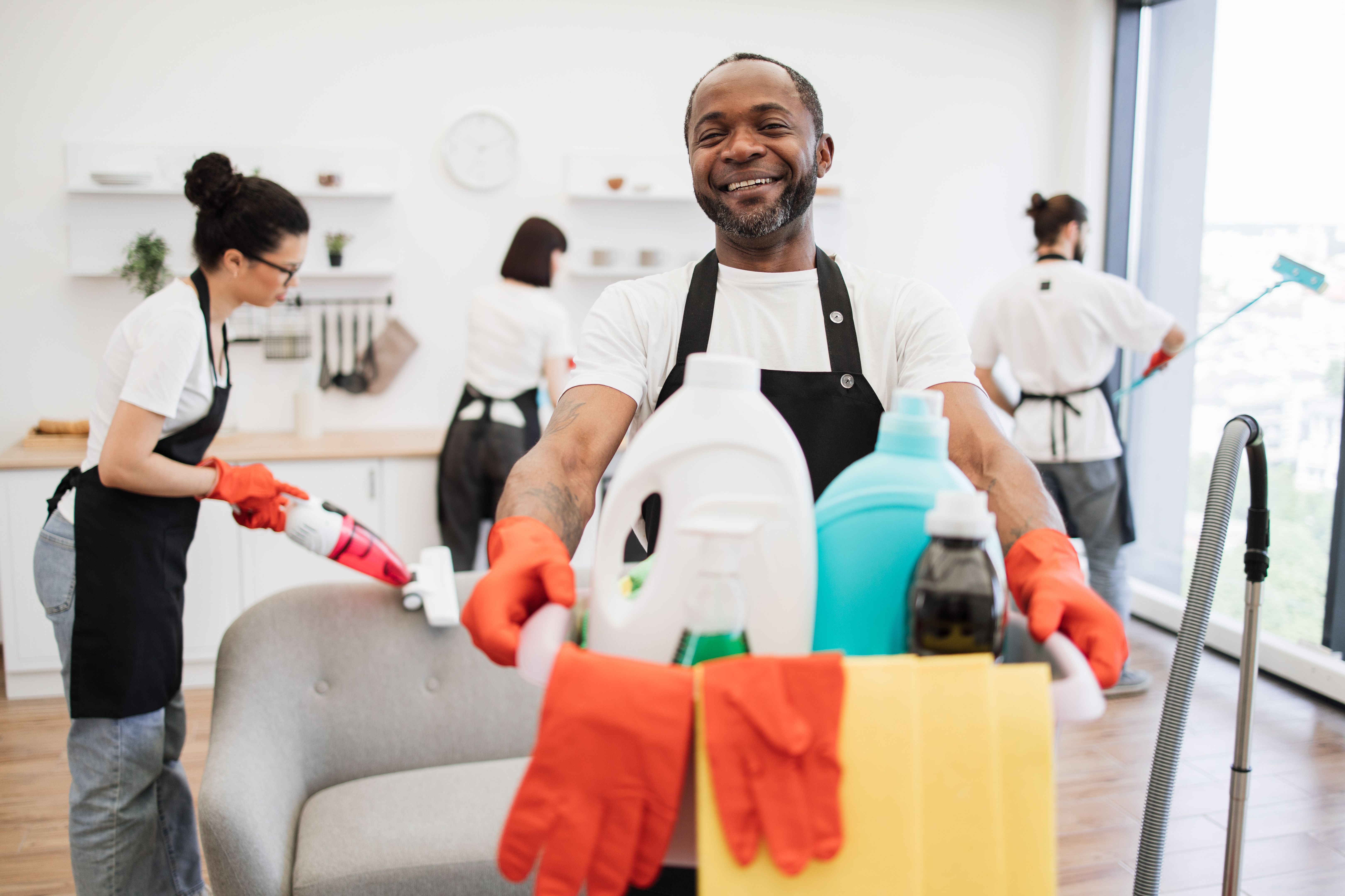 African man professional cleaning worker holding a bucket with detergents. African man professional cleaning worker holding a bucket with detergents.