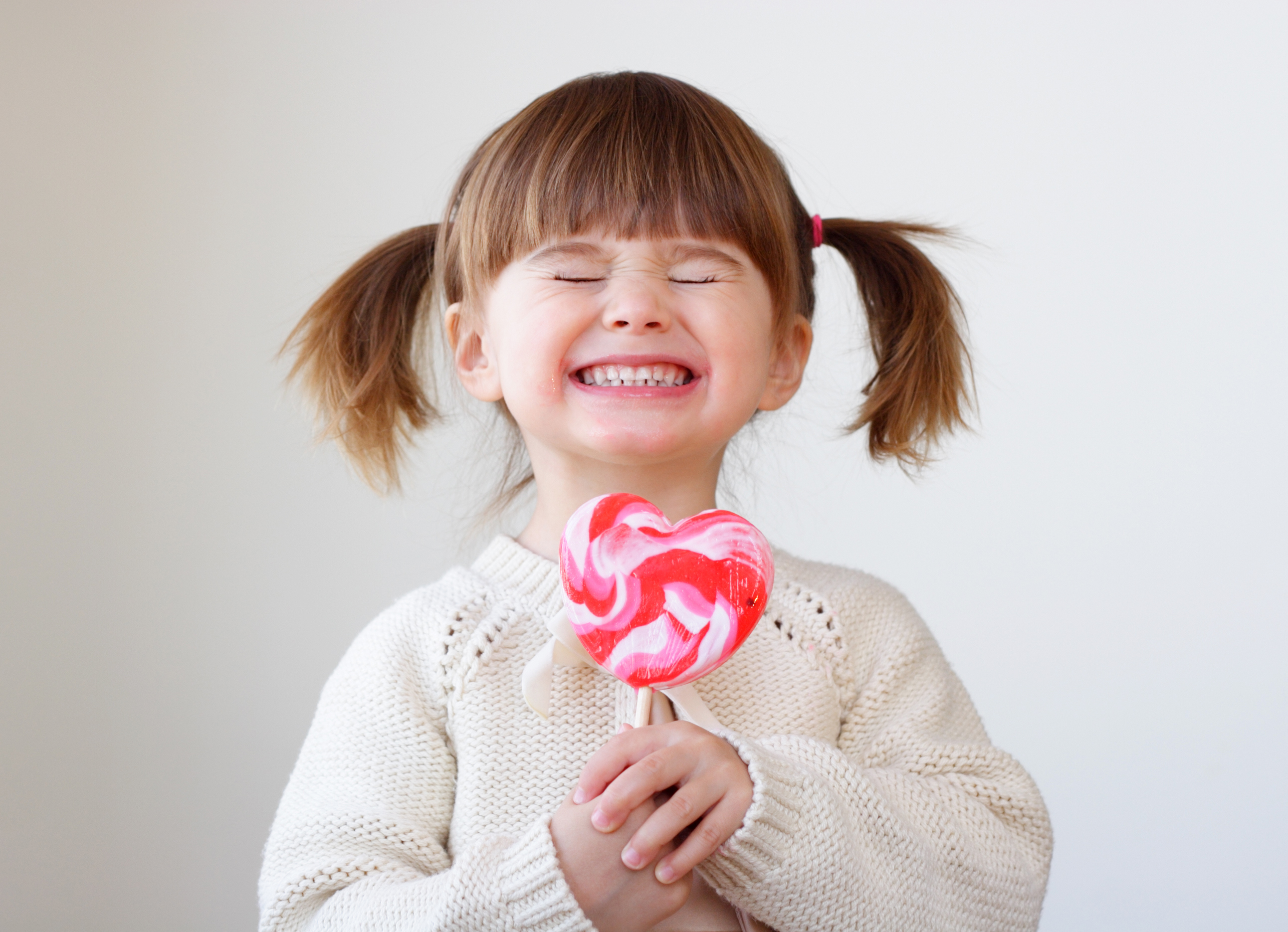 Giddy young girl with a heart-shaped lollipop