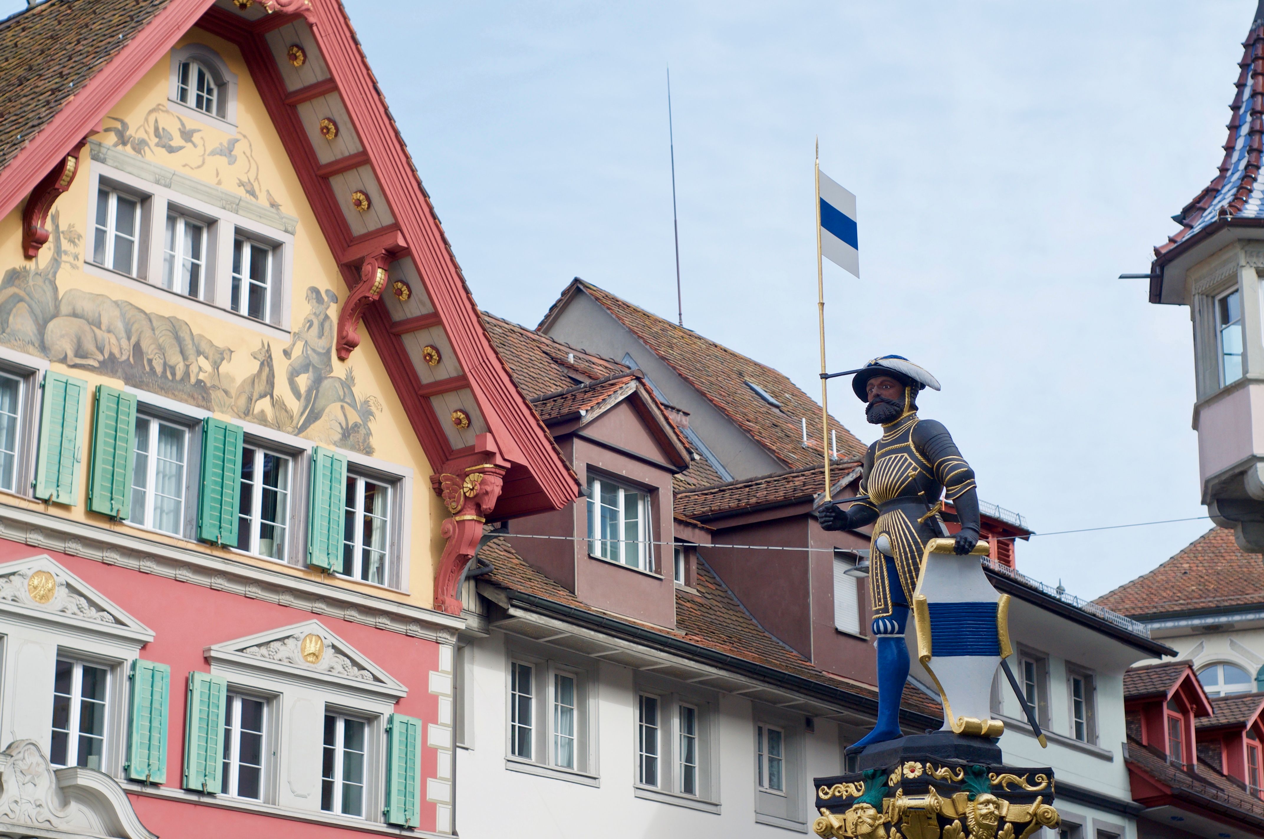 Kolinbrunnen fountain statue with traditional buildings in Zug