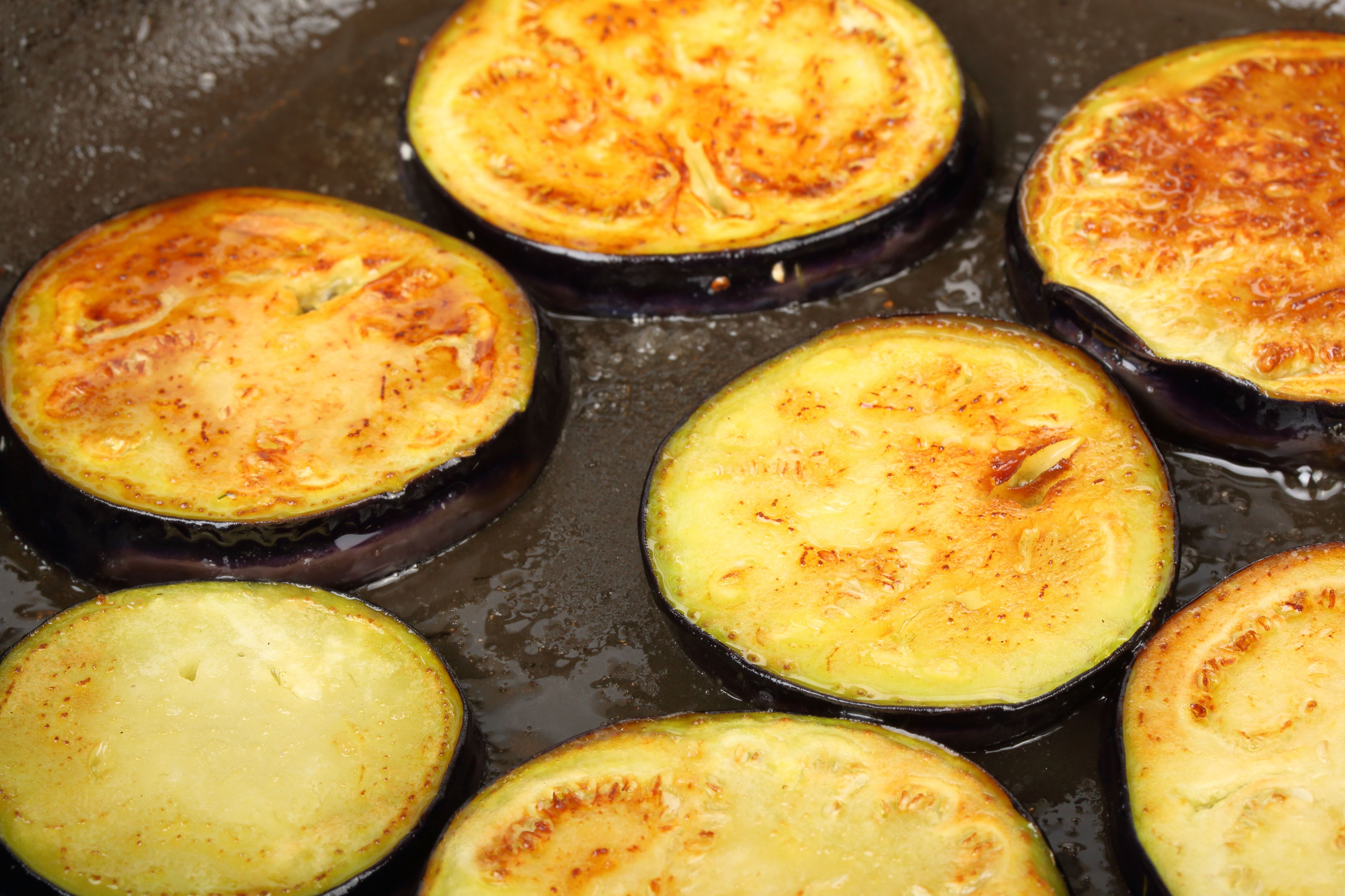 Sliced eggplants fry in a pot with oil