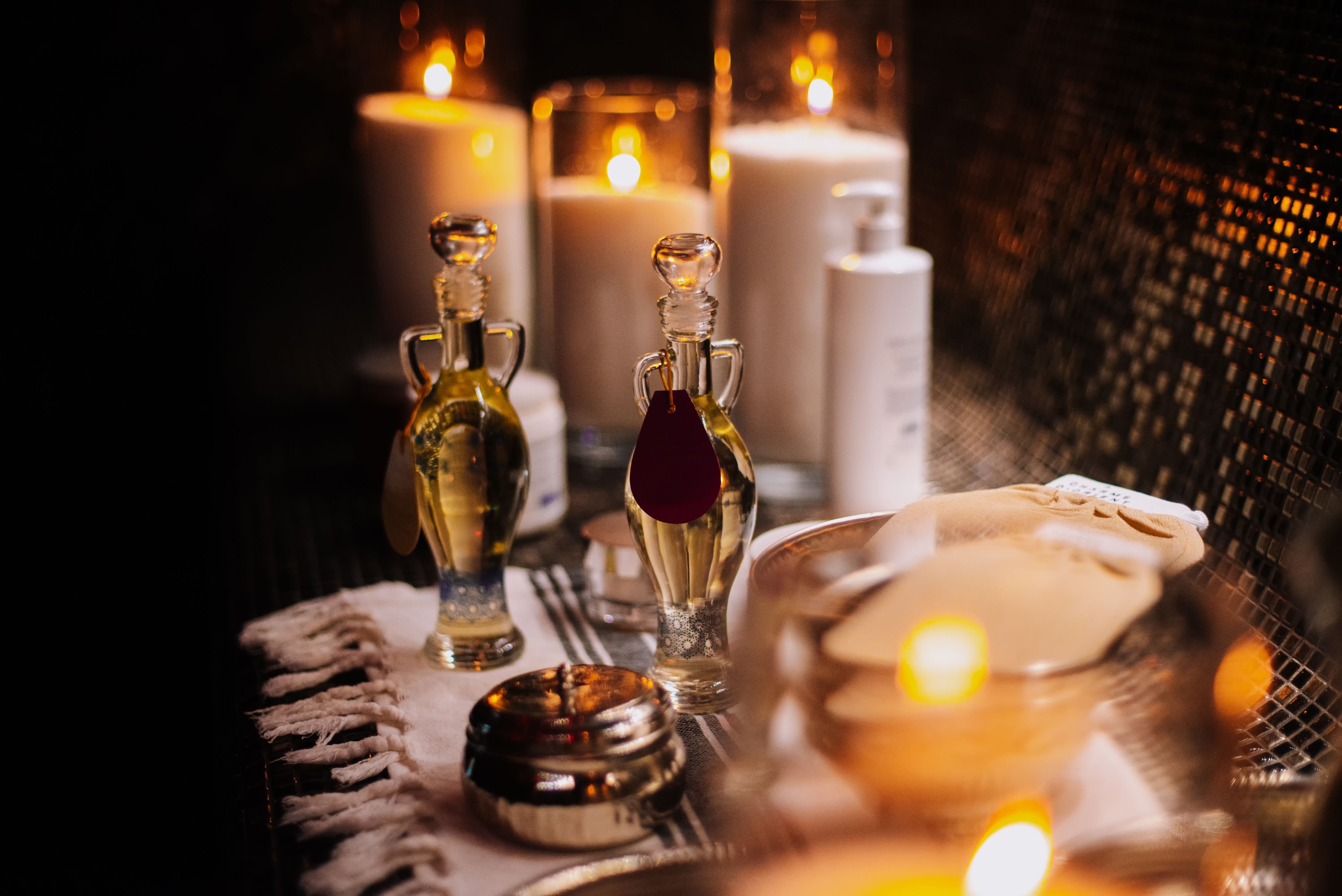 Essential oils with various herbs and flowers near candles