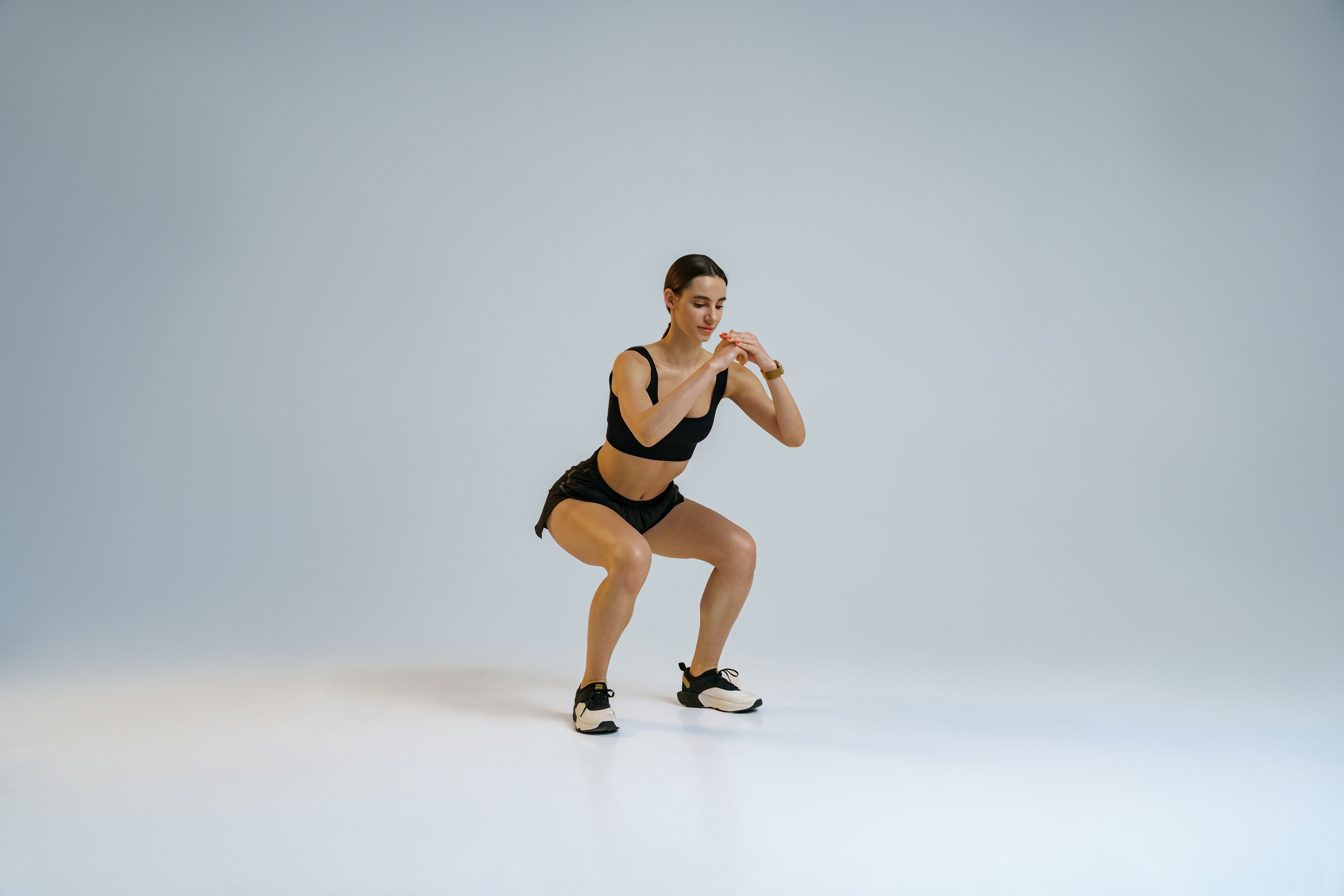 Fitness woman doing deep squat exercise on studio background. Workout Concept