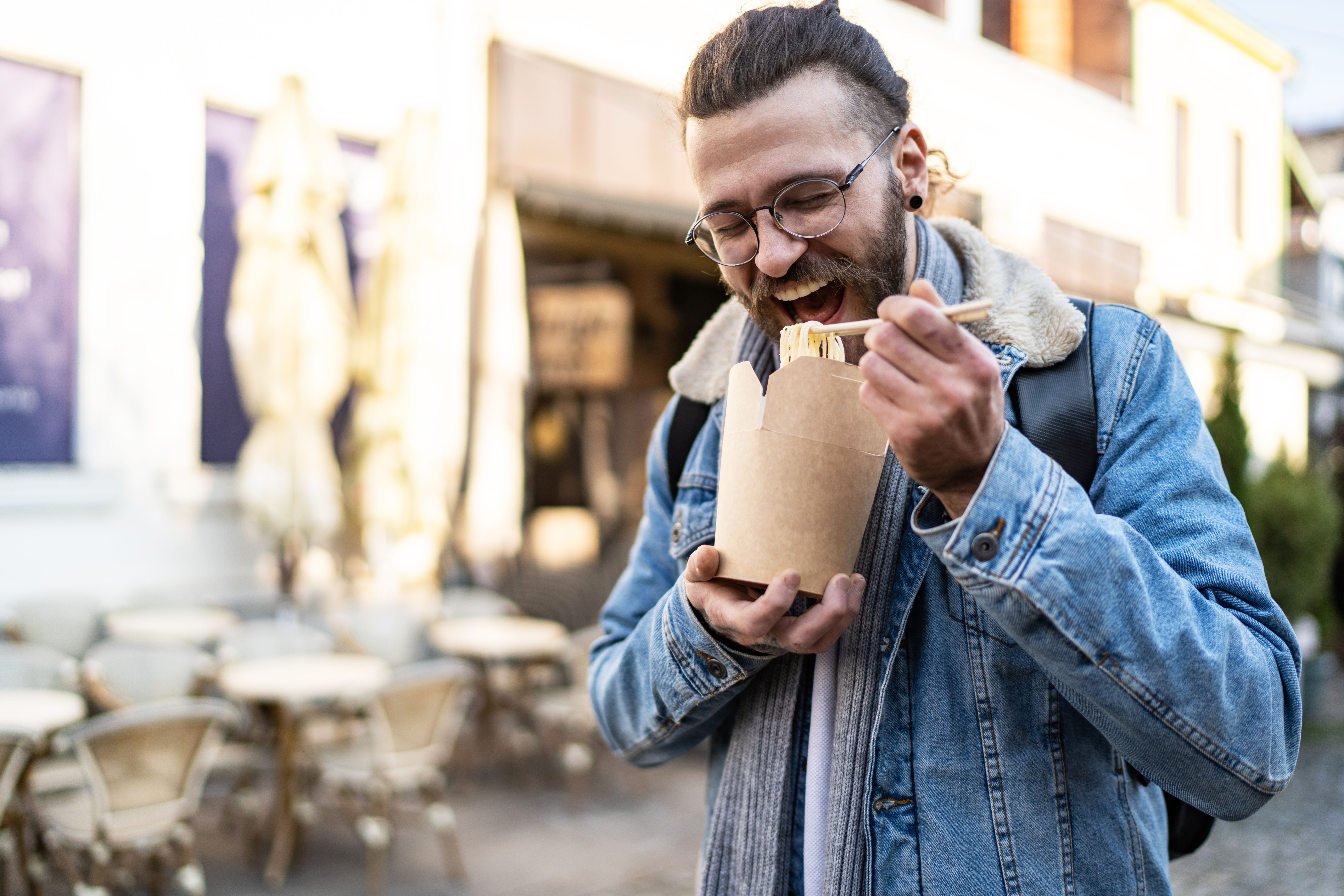 Modern happy young man eating spaghetti from a compostable to gopackage Modern happy young man eating spaghetti from a compostable to gopackage