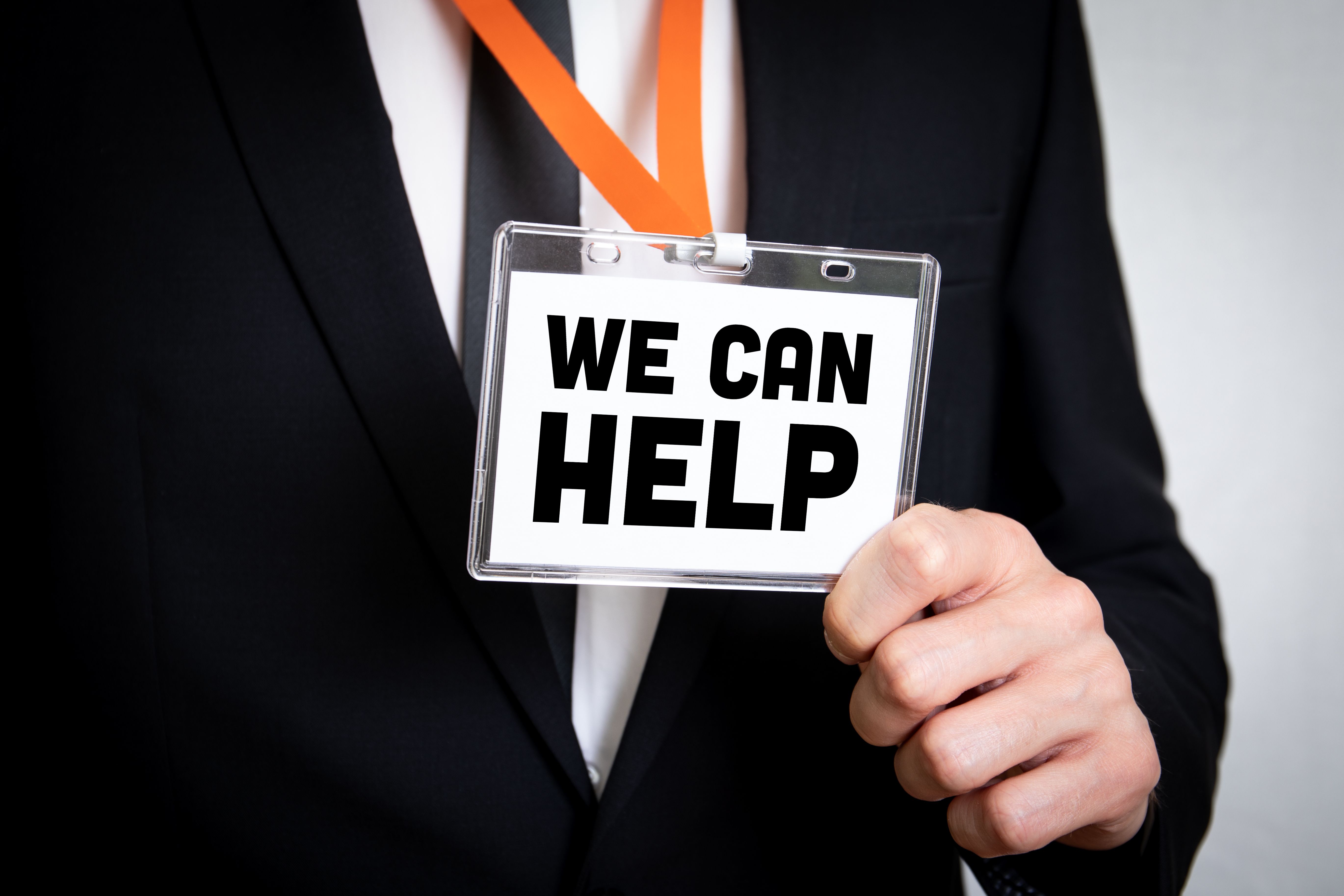 We Can Help. Businessman in suit and with security identity name card on a lanyard We Can Help. Businessman in suit and with security identity name card on a lanyard