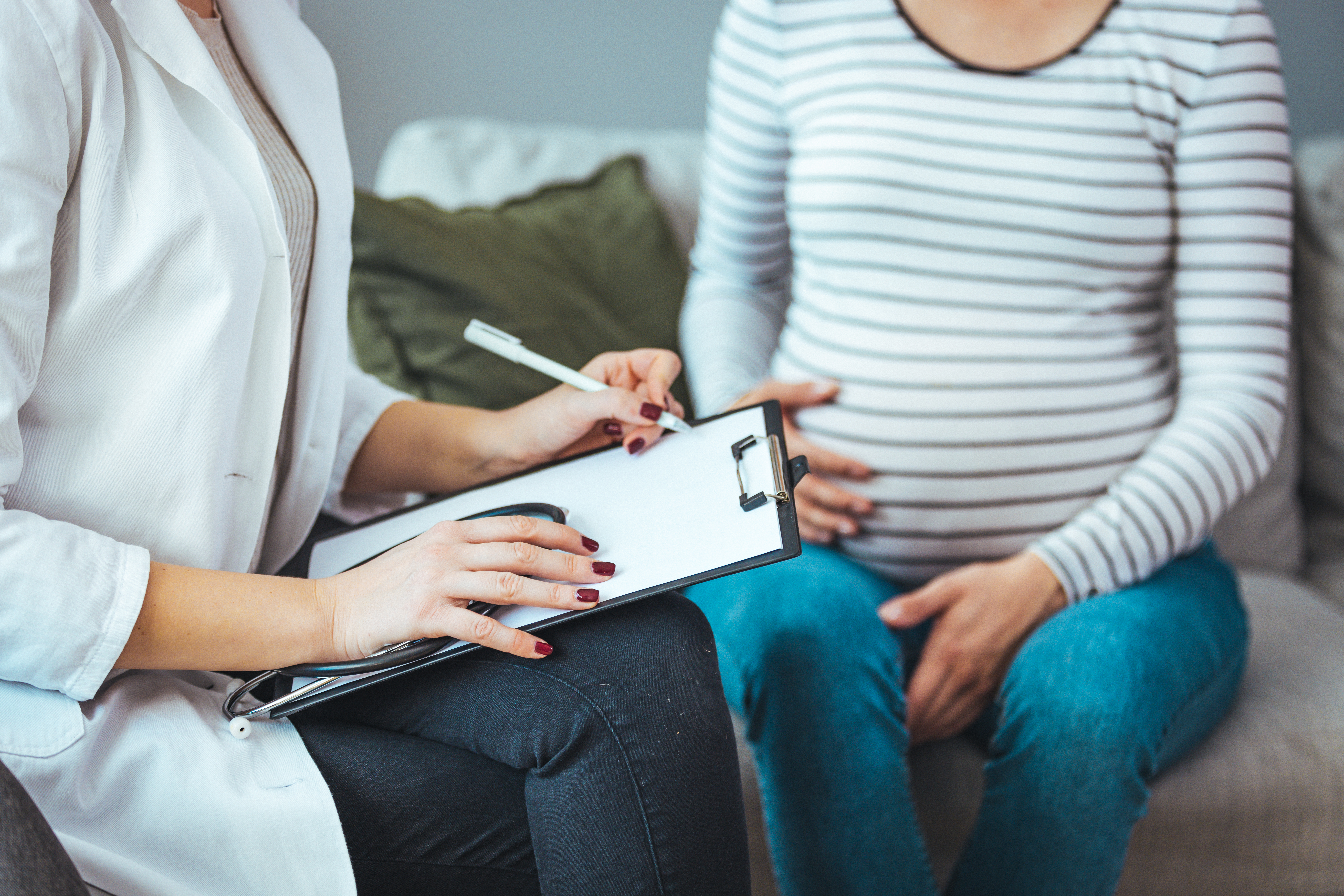 A pregnant Caucasian woman is indoors in a doctor's office. A pregnant Caucasian woman is indoors in a doctor's office.