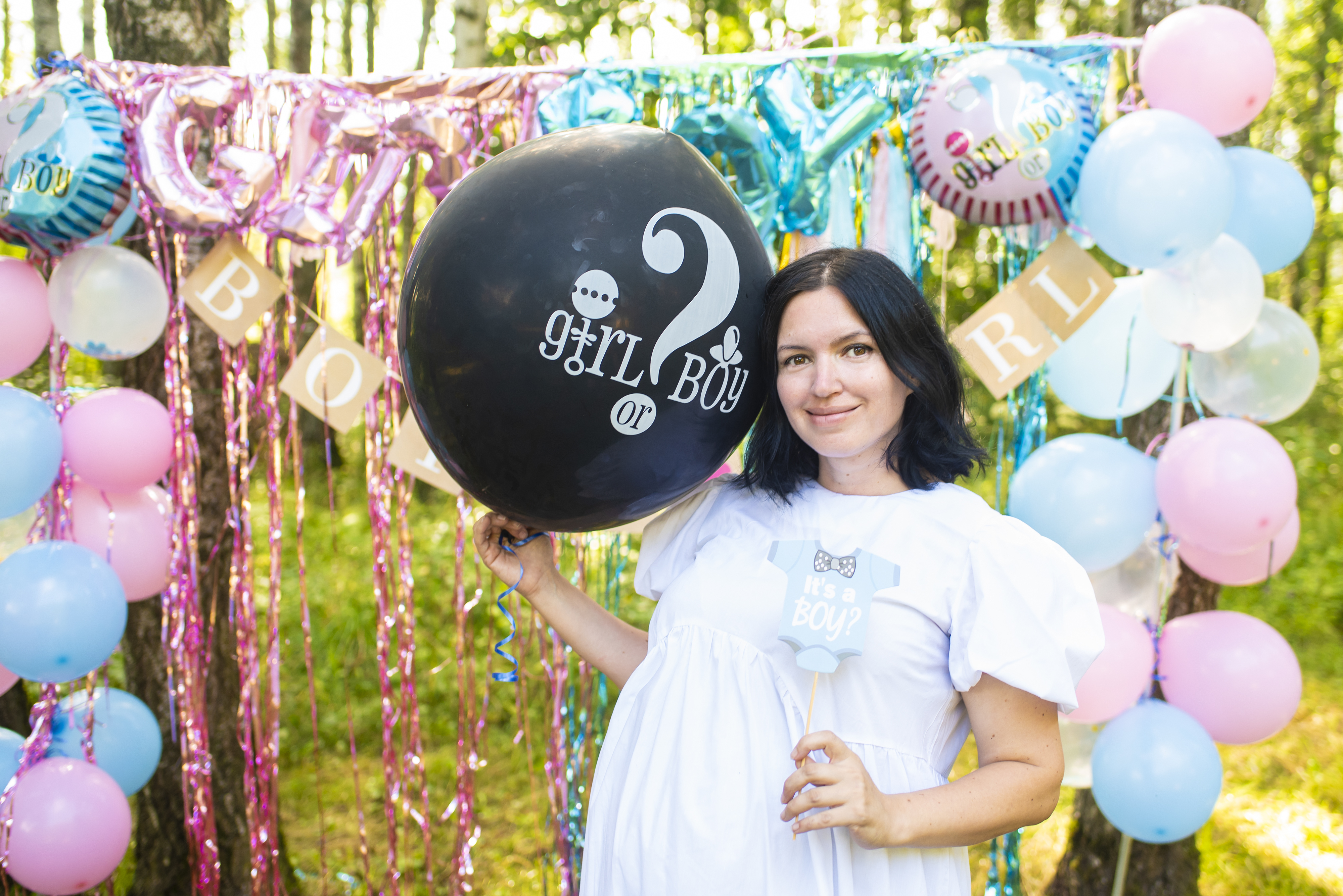 Pregnant 41 year old woman at Gender Reveal Party, holding black balloon with 