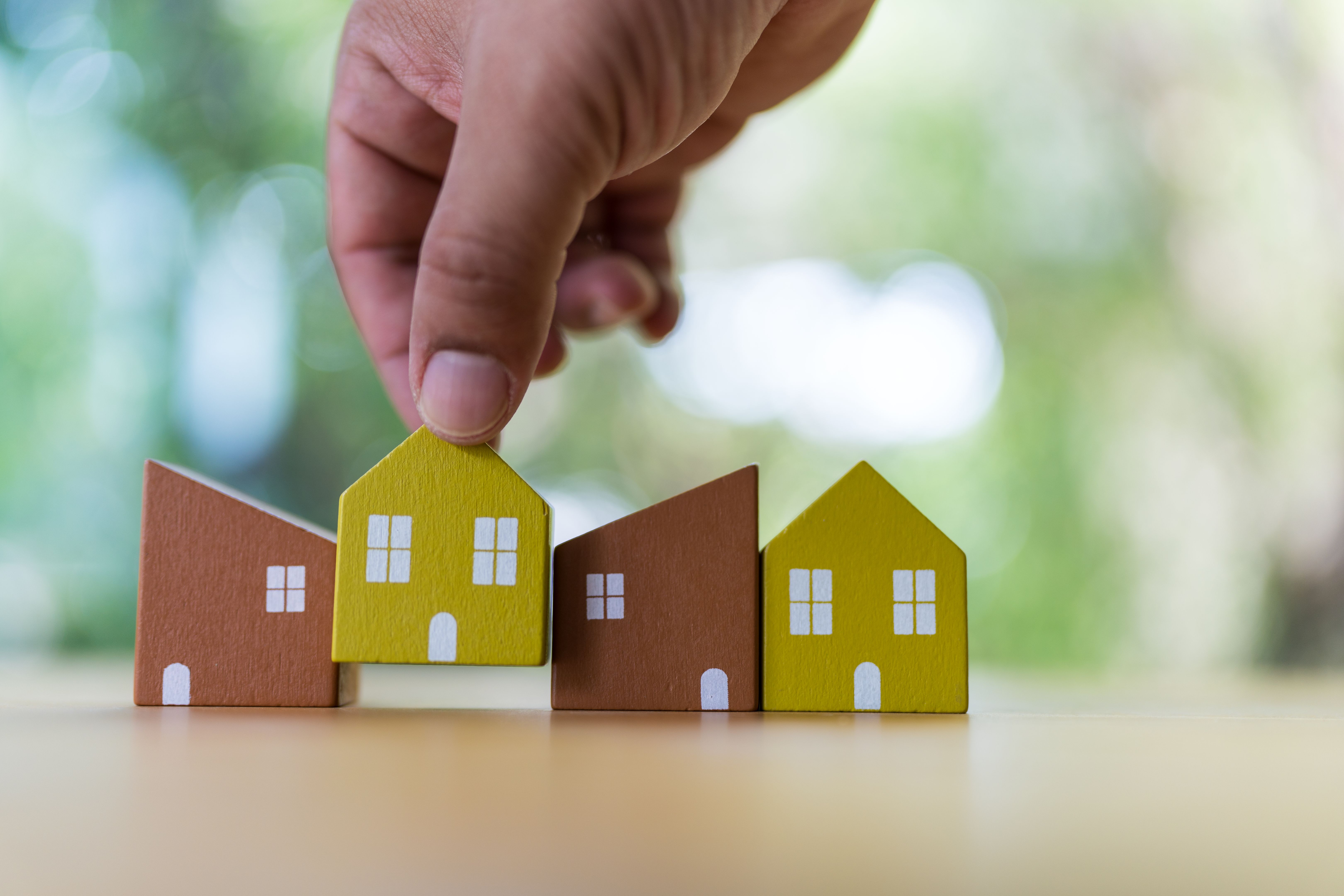 Man chooses a small wooden house from the model. Plan to buy property Concept of choose the best.