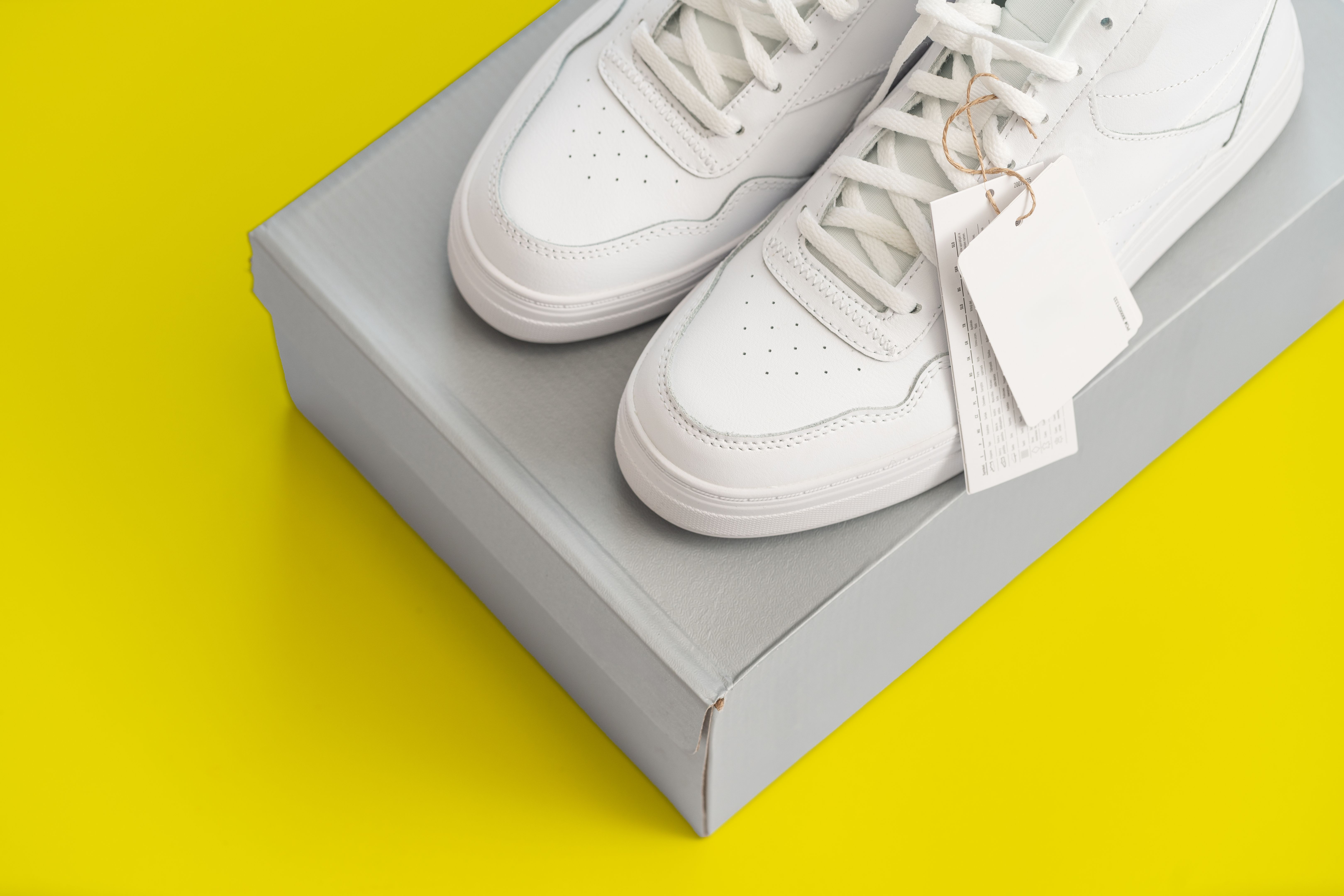White Sneakers on Shoe Box With Bright Yellow Background