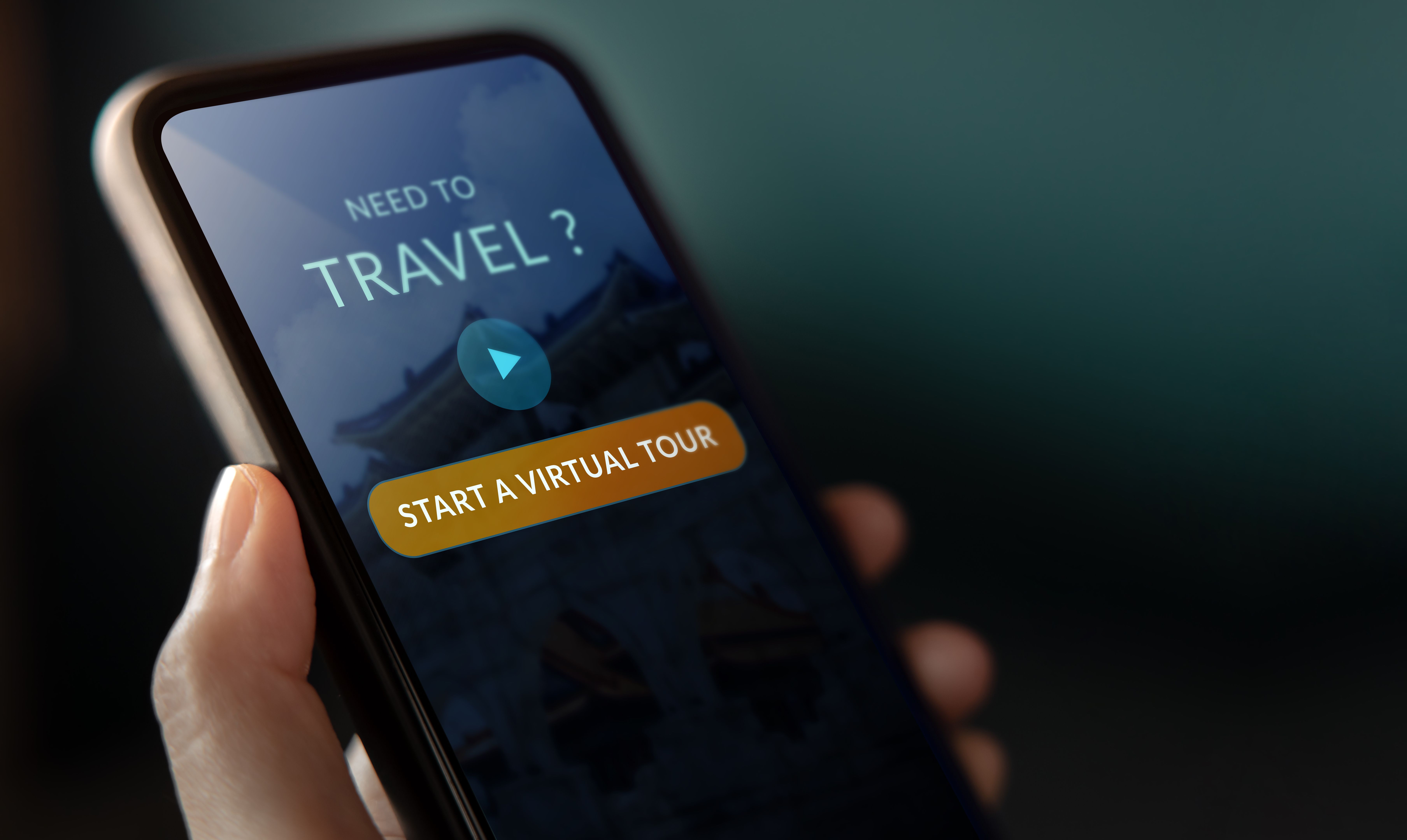 A person holding a smartphone displaying a screen that reads “Need to travel? Start a virtual tour,” symbolizing digital exploration and virtual travel experiences.