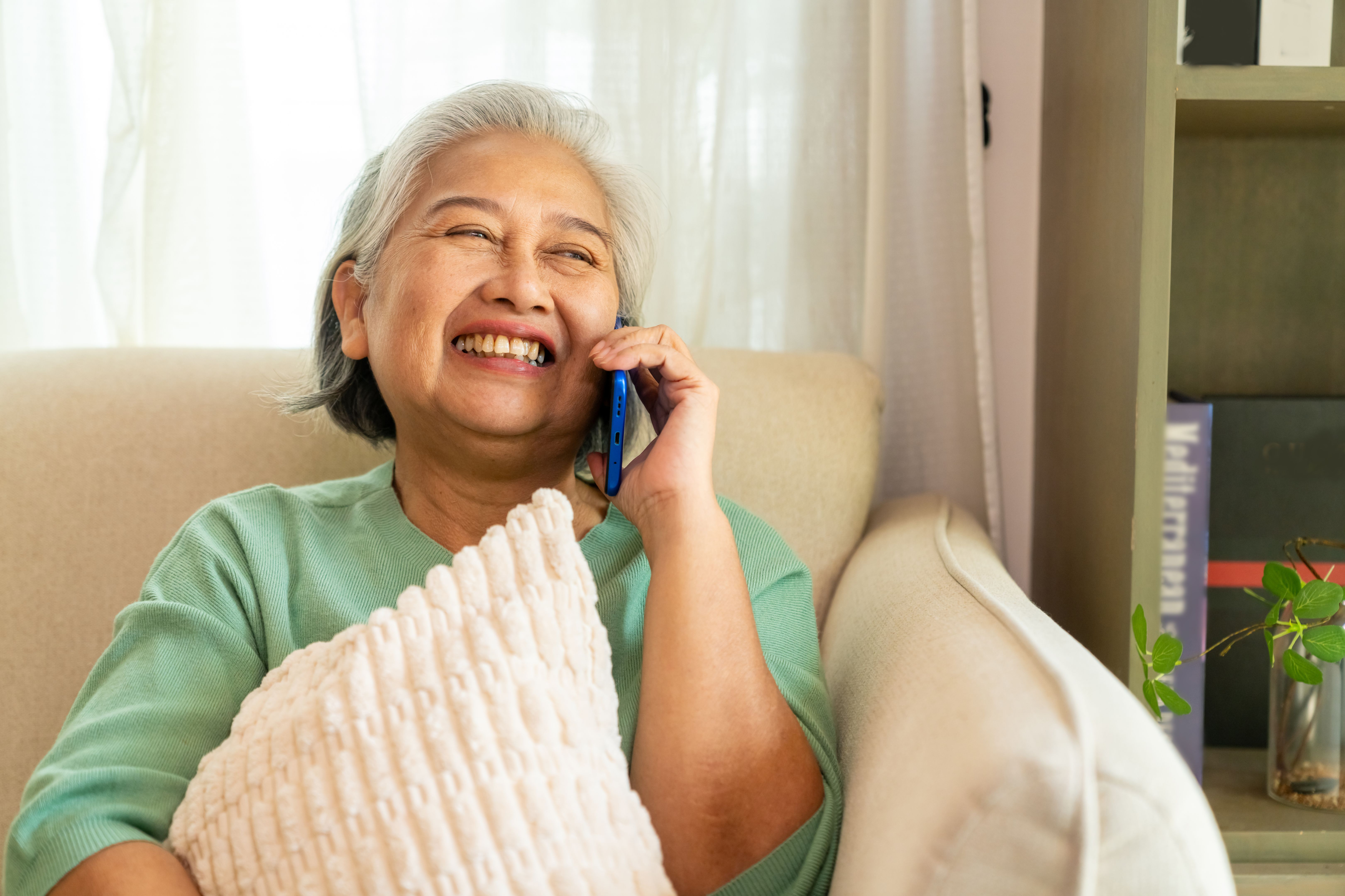 Asian senior woman speaking on mobile phone at home.