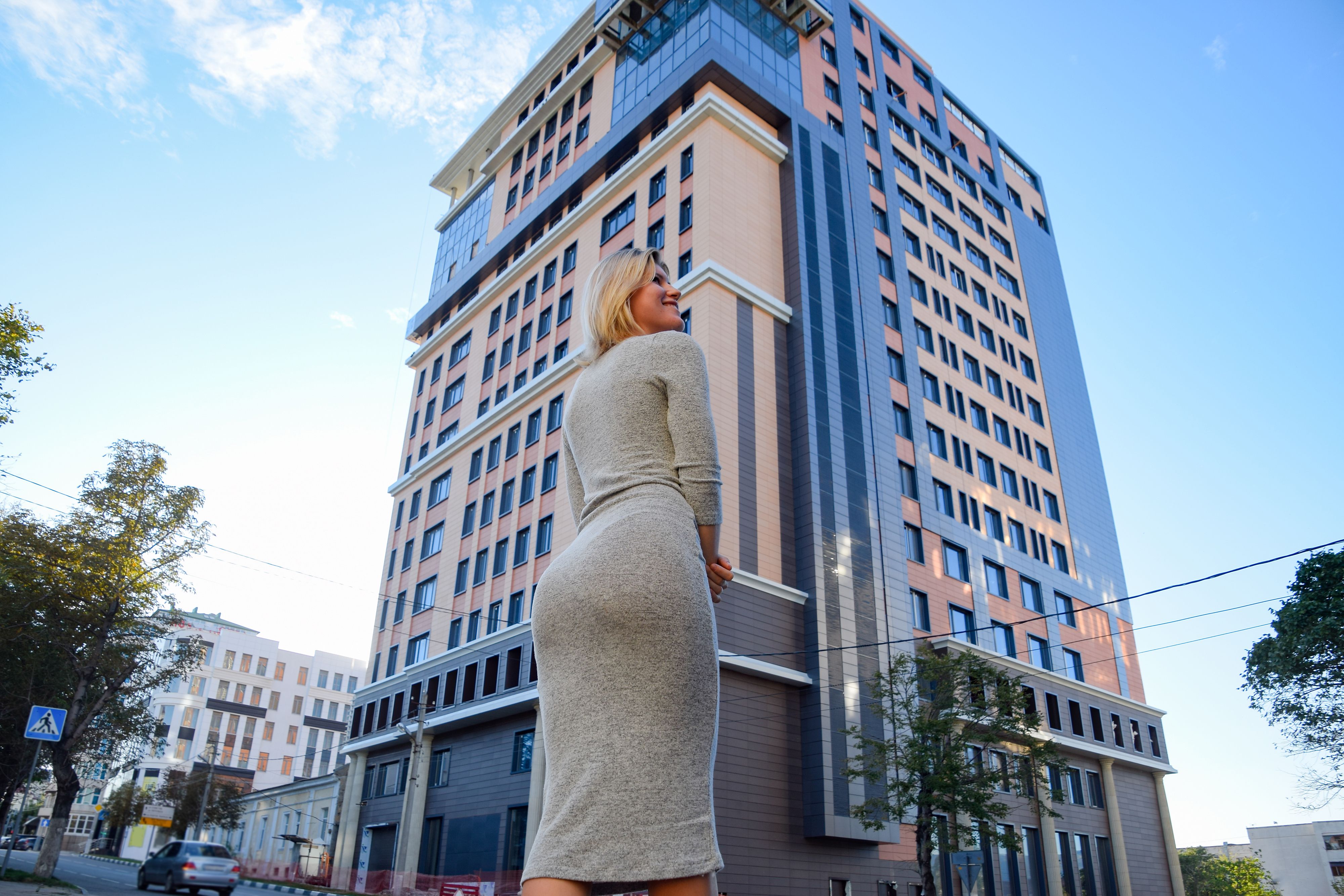 A girl with a beautiful figure in a gray dress near a tall building. A girl with a beautiful figure in a gray dress near a tall building.