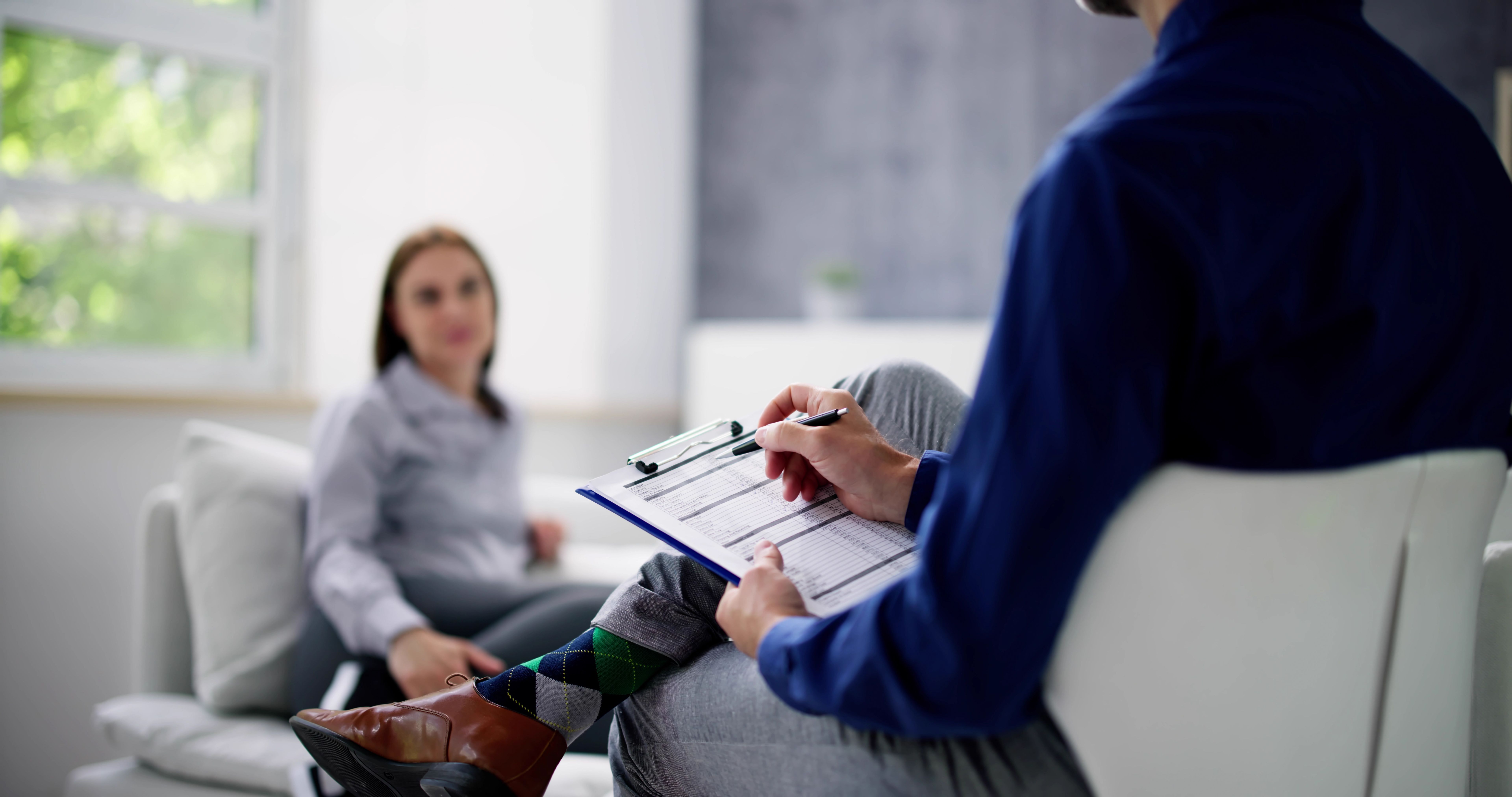 Young Woman Sitting Near Psychologist With Clipboard