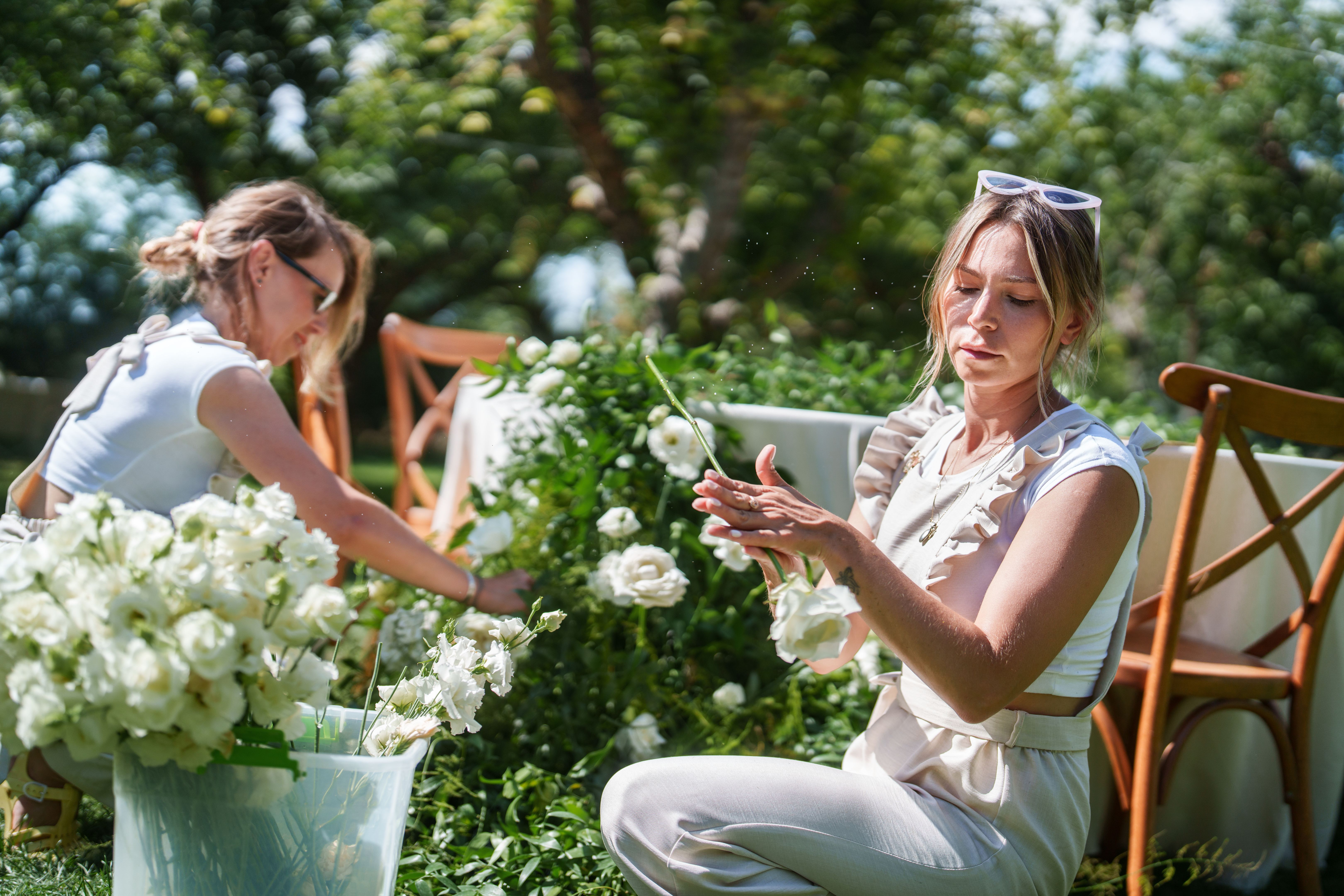 The wedding planning team is placing flowers on the flower garlands of the dining tables.