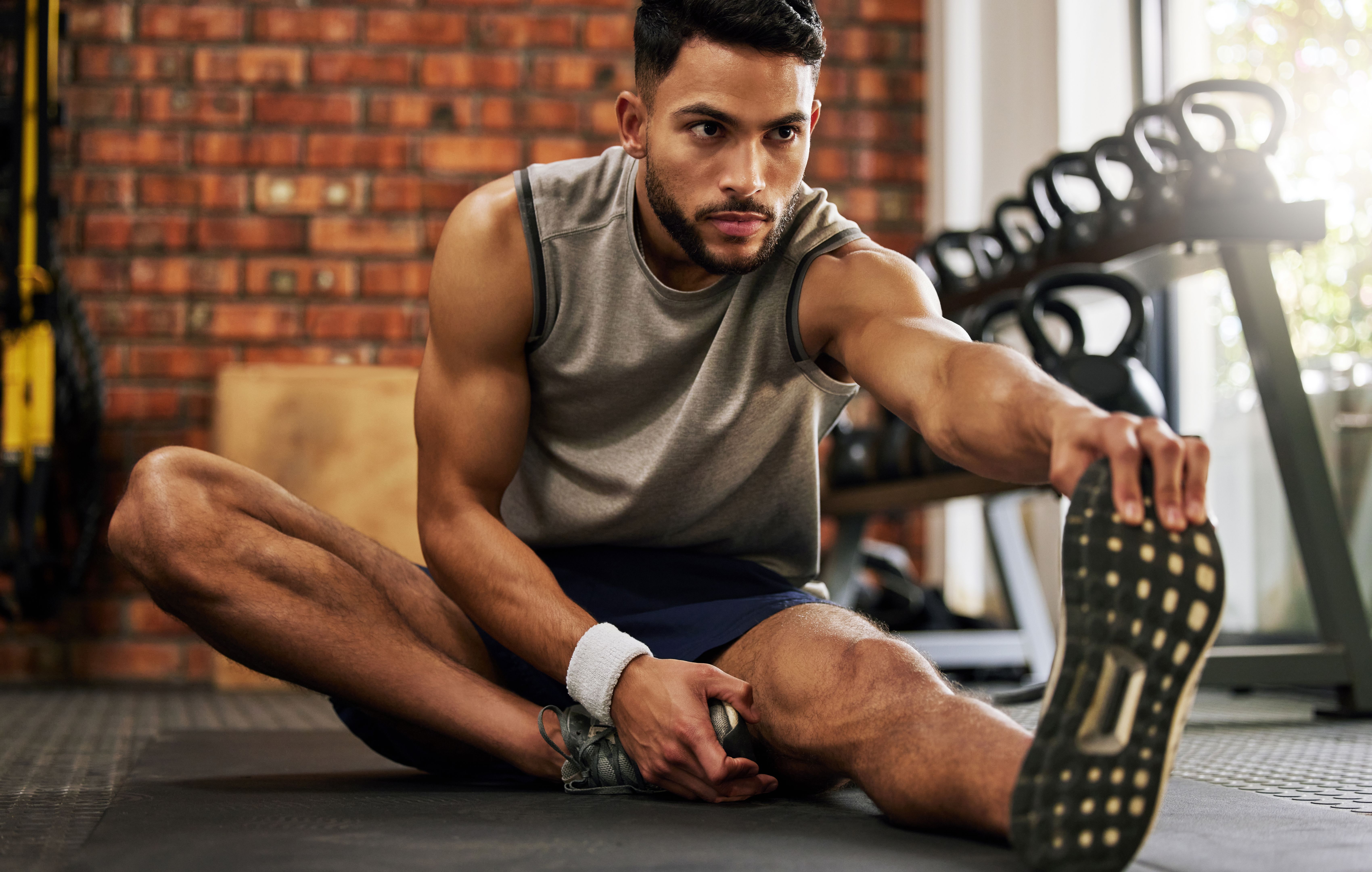 Shot of a young man stretching before his workout in the gym Shot of a young man stretching before his workout in the gym