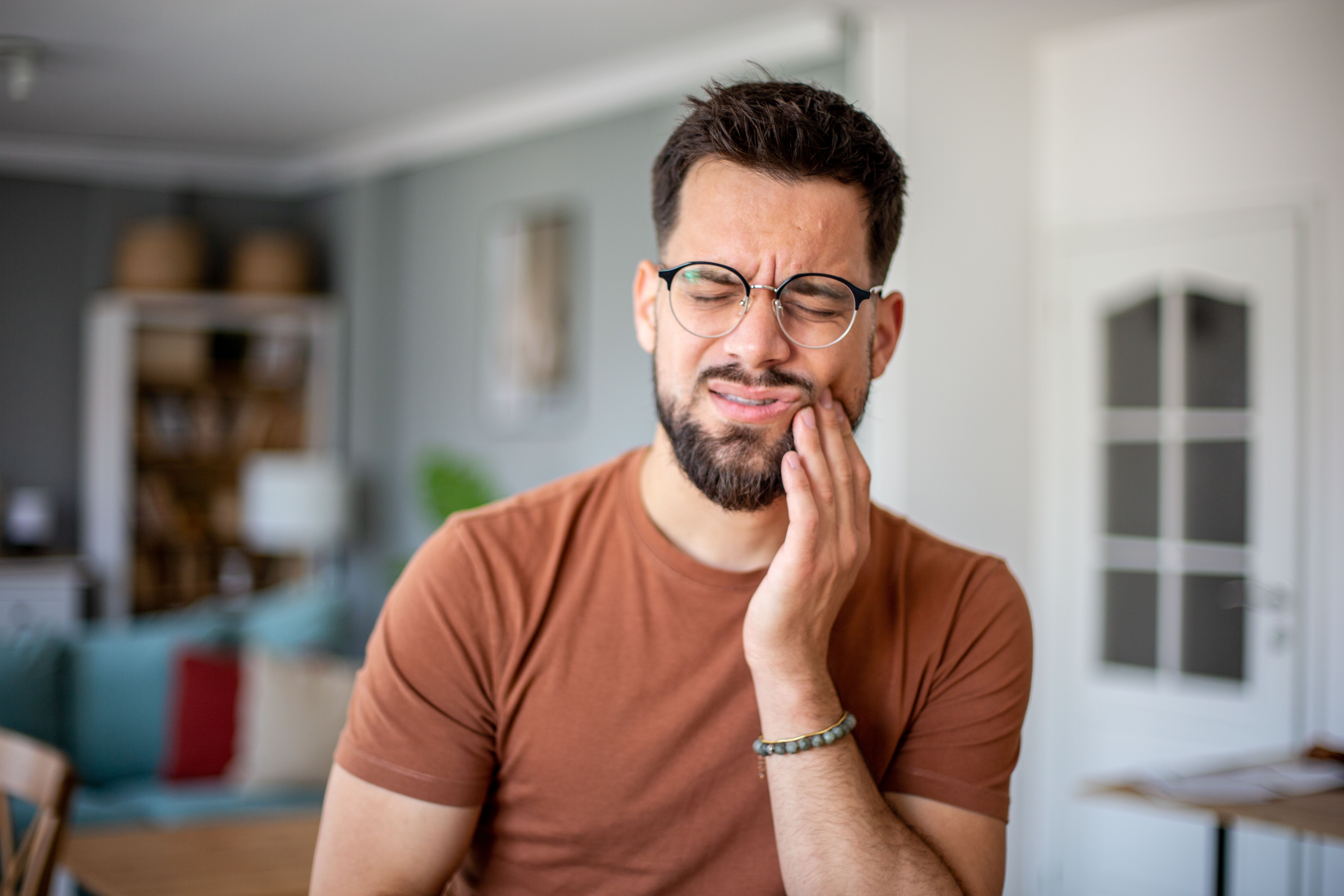Joven que sufre de un fuerte dolor de muelas en casa