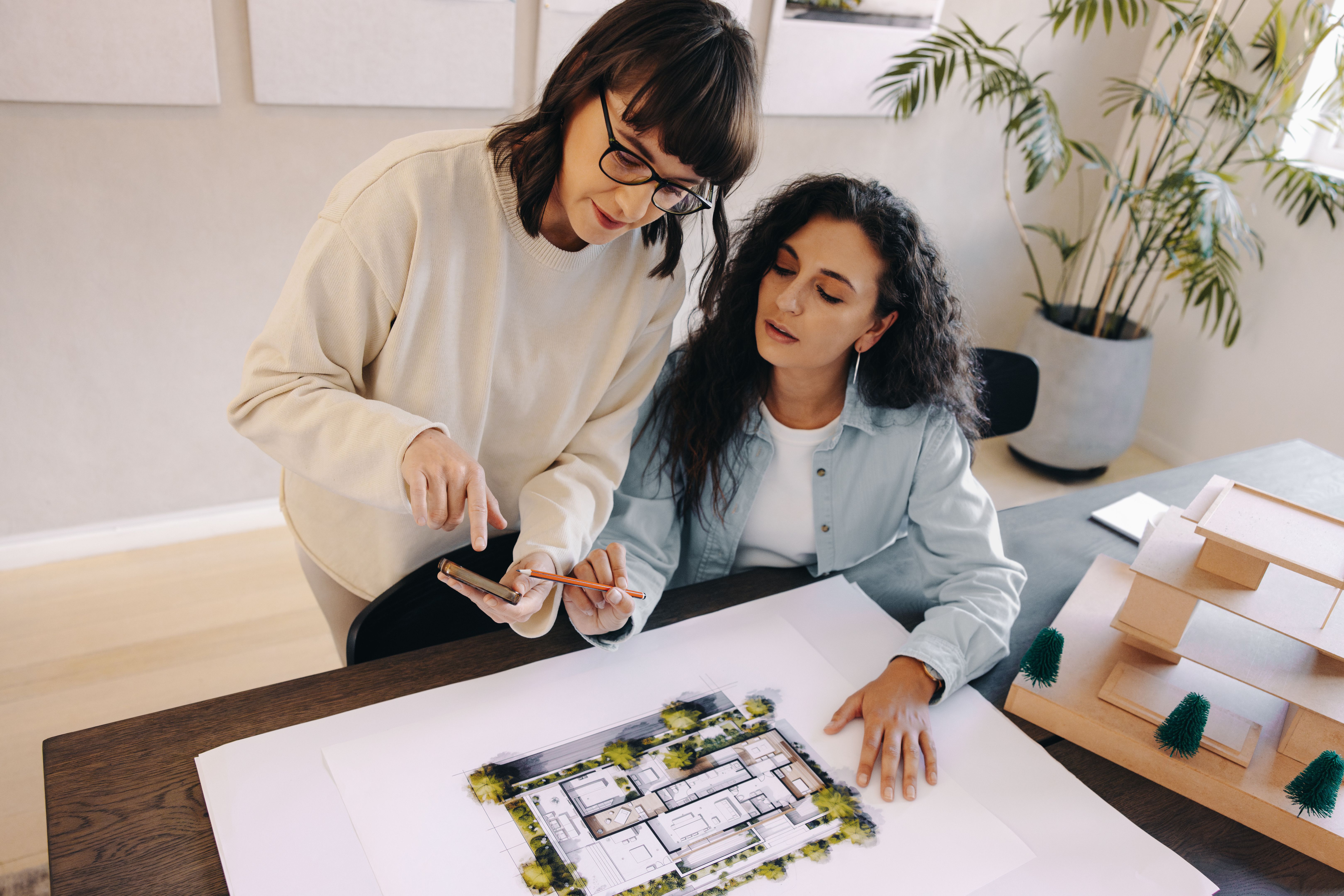 Woman showing colleague plans and discussing inspiration using a smartphone
