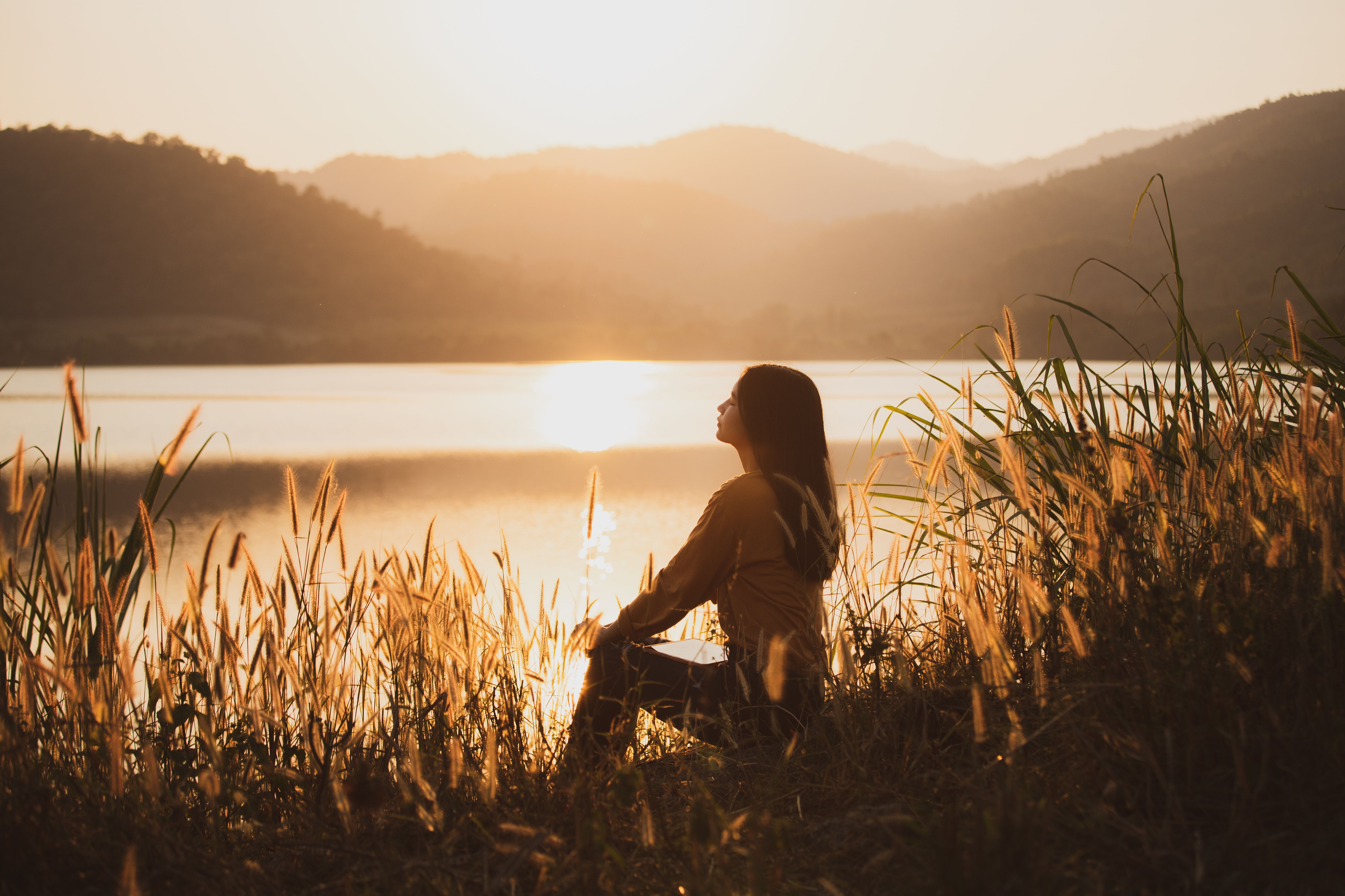 Rear view of a woman tourist sitting at a walkway near the reservoir.