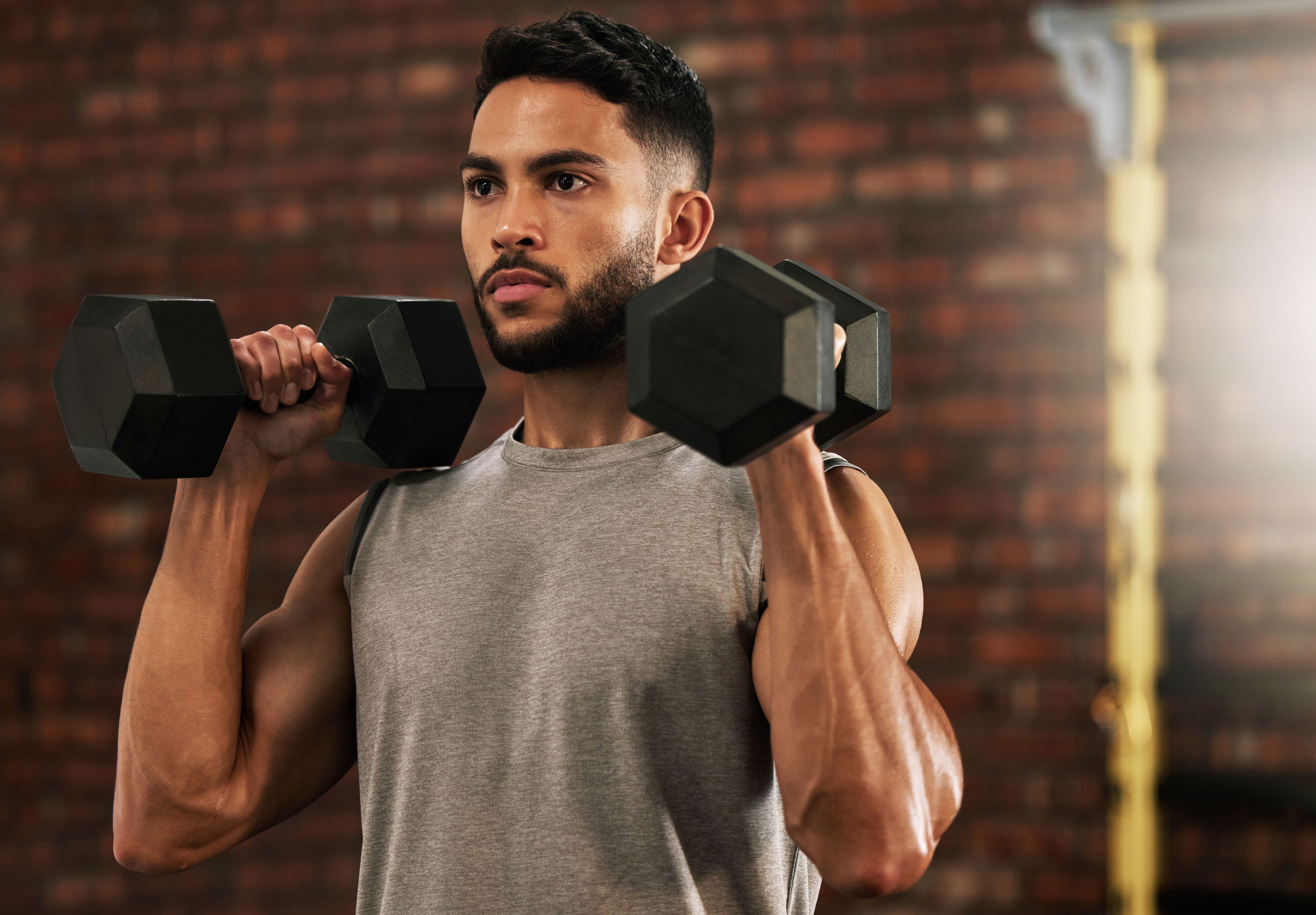Shot of a young man working out with dumbbells in a gym Shot of a young man working out with dumbbells in a gym