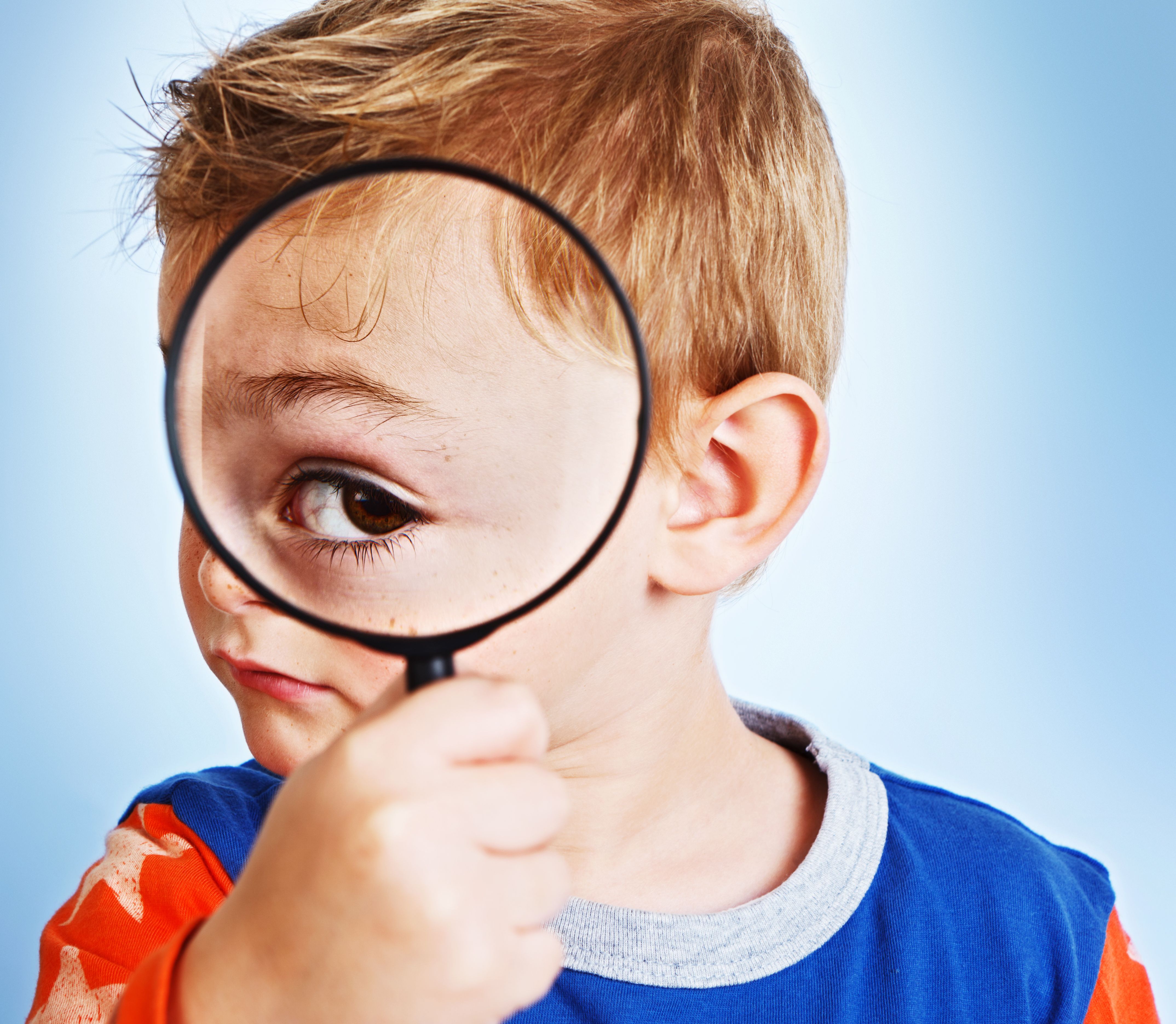 Magnifying glass enlarges playful boy's eye enormously: young Sherlock Holmes Magnifying glass enlarges playful boy's eye enormously: young Sherlock Holmes