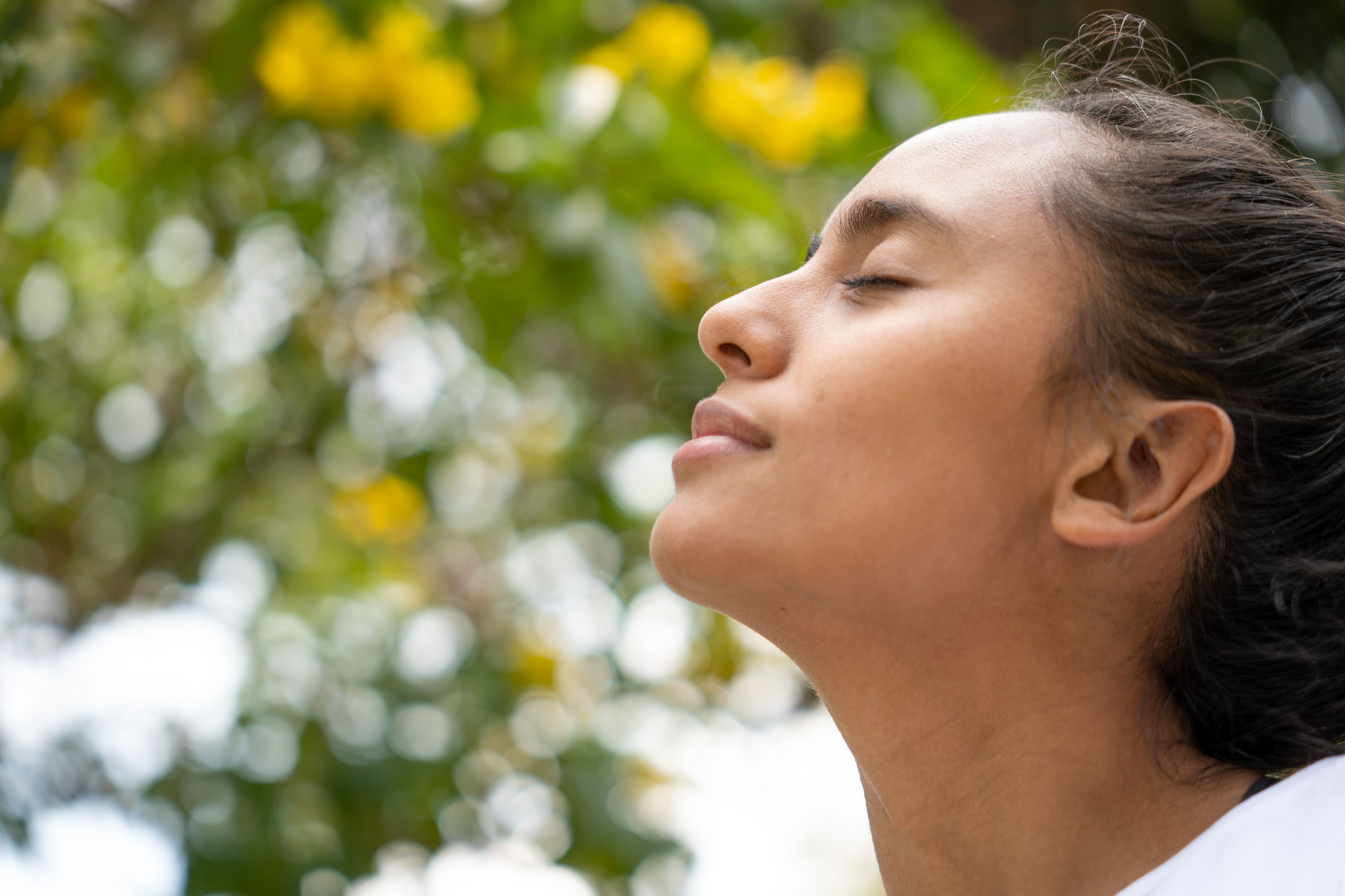 Gros plan d’une jeune femme à côté d’un arbre dans la forêt avec un t-shirt blanc par une journée ensoleillée