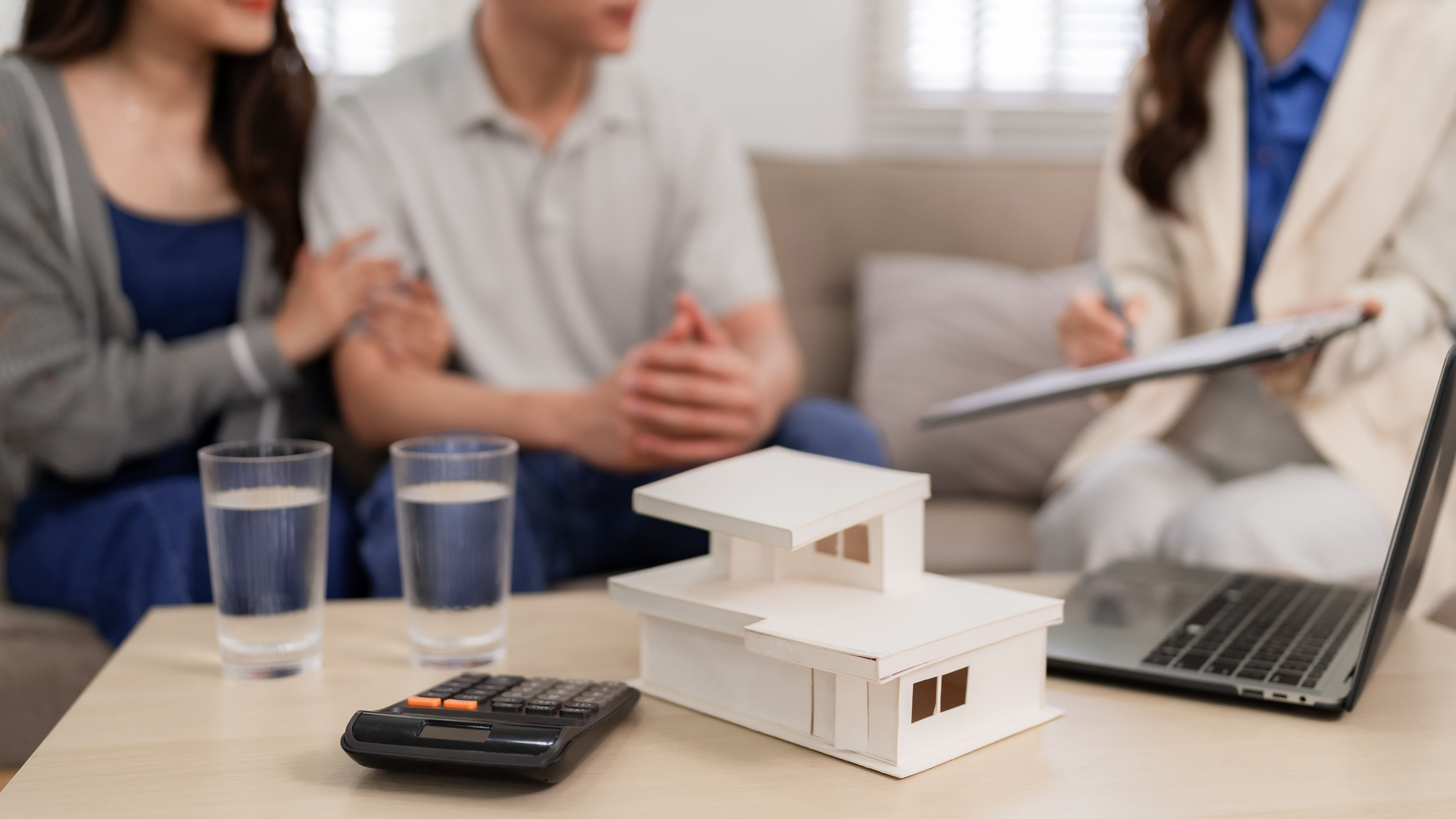 Real estate agent home consultation Asian adult couple discussing property investment with house model financial planning at cozy living room Real estate agent home consultation Asian adult couple discussing property investment with house model financial planning at cozy living room