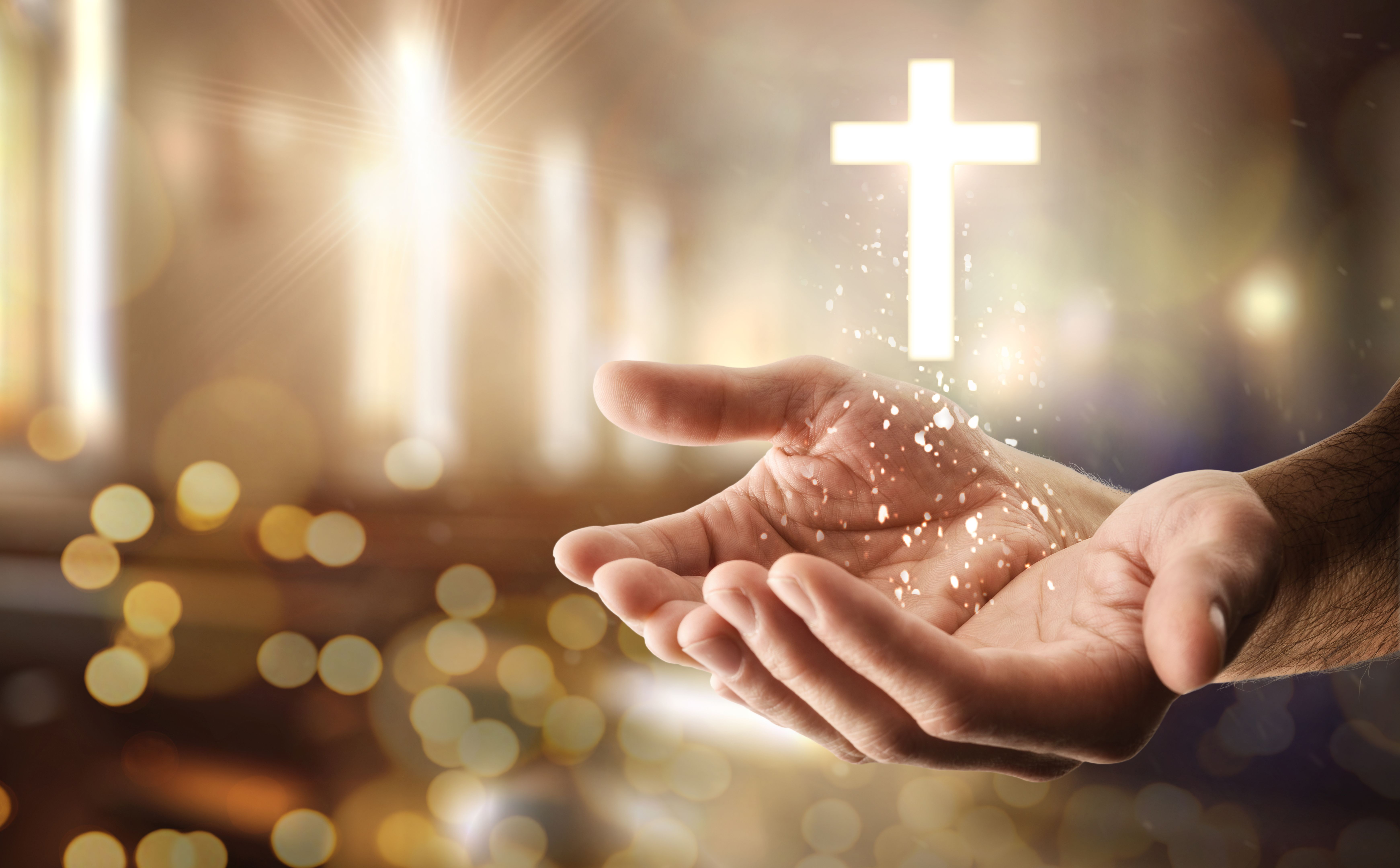 Hands and cross floating with glitters and religious background