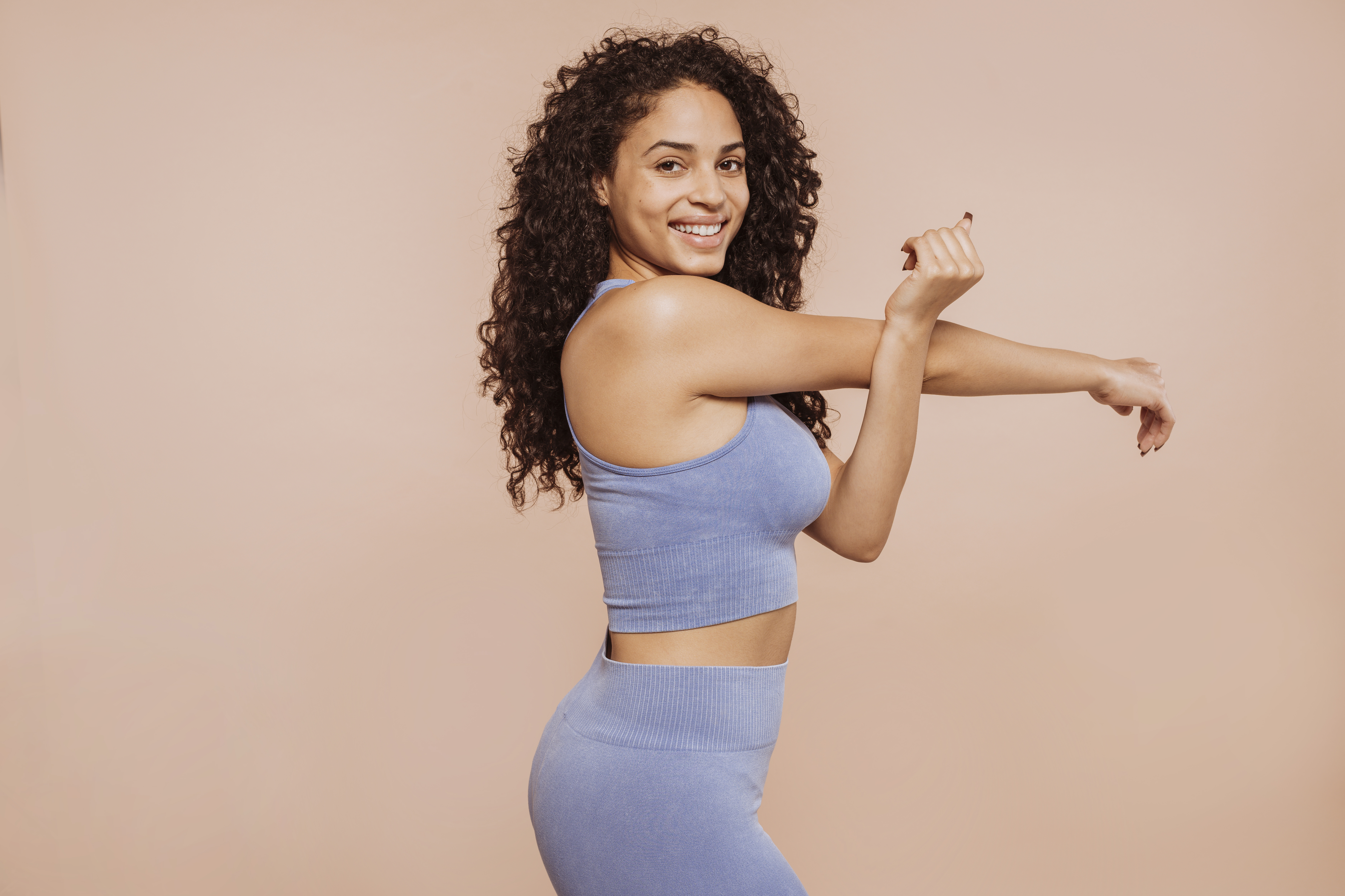 Young curly sportswoman stretching arms Young curly sportswoman stretching arms